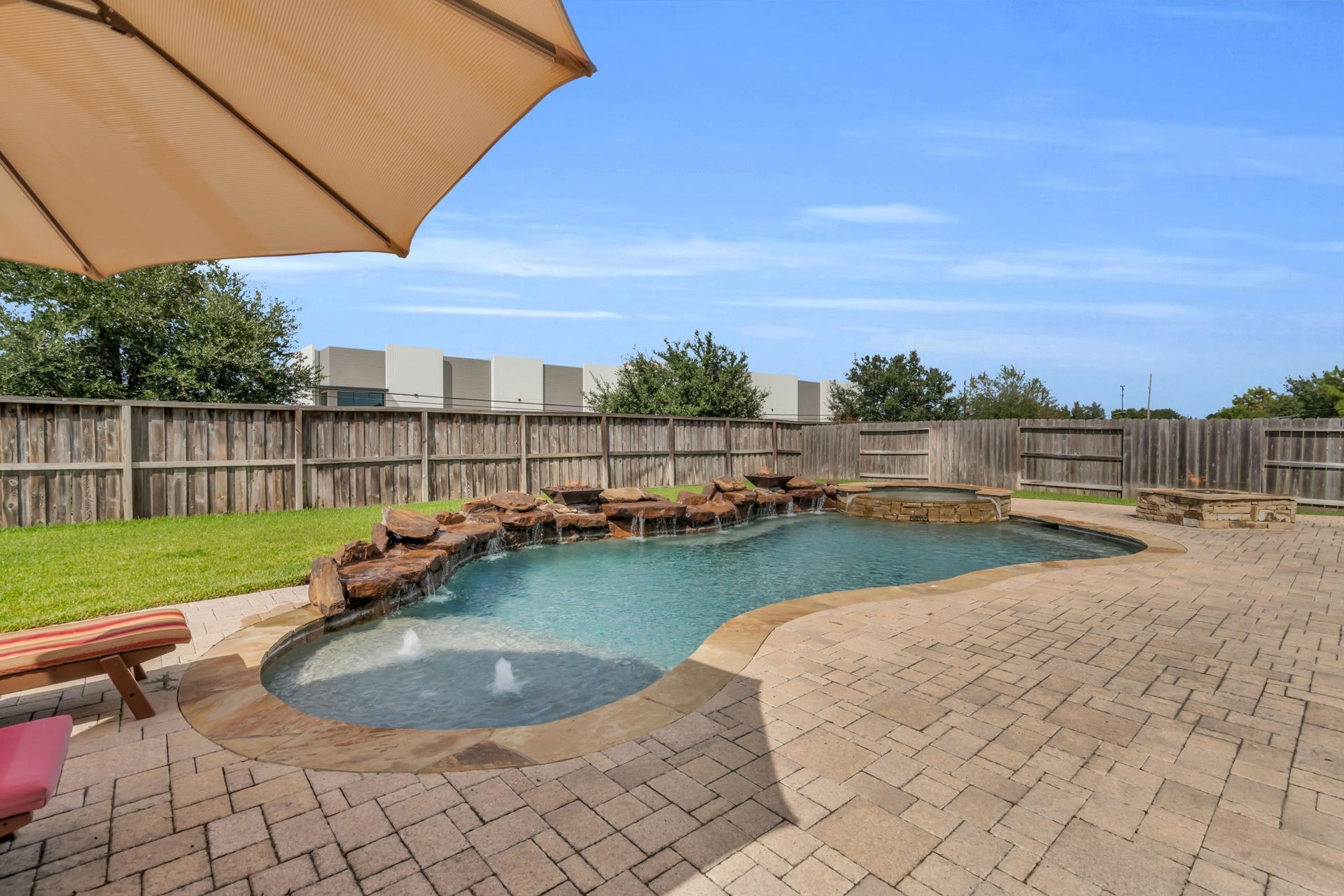 Sparkling pool showcases rock waterfall accents, a relaxing spa, and fire features.