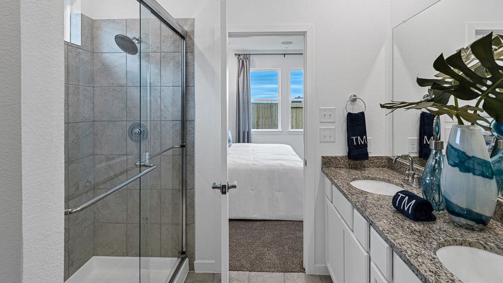 7334 Grand Mason Drive, Cypress, TX 77433 Primary ensuite bath has double vanities and a walk-in shower with glass enclosure.