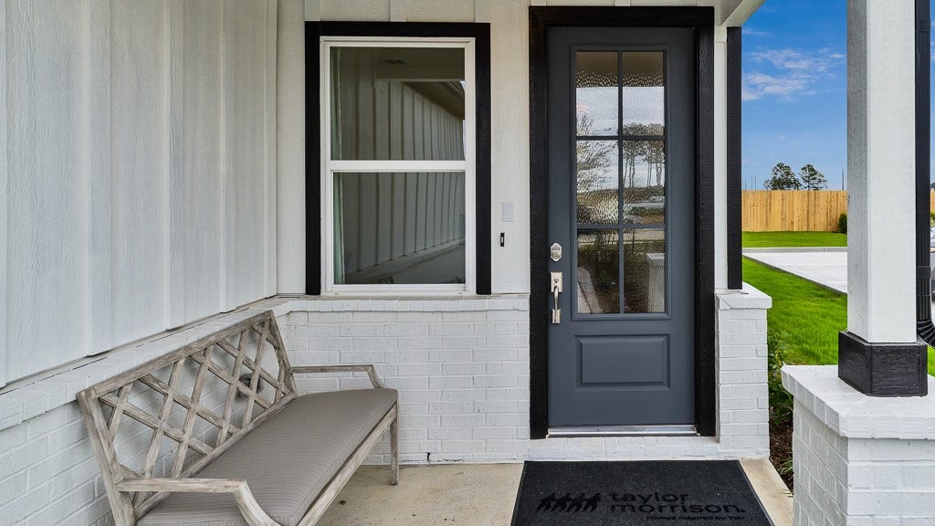 7334 Grand Mason Drive, Cypress, TX 77433 Welcoming front porch entry has crisp white vertical slat siding with brick wainscoting and a striking 6-lite custom front door in black.