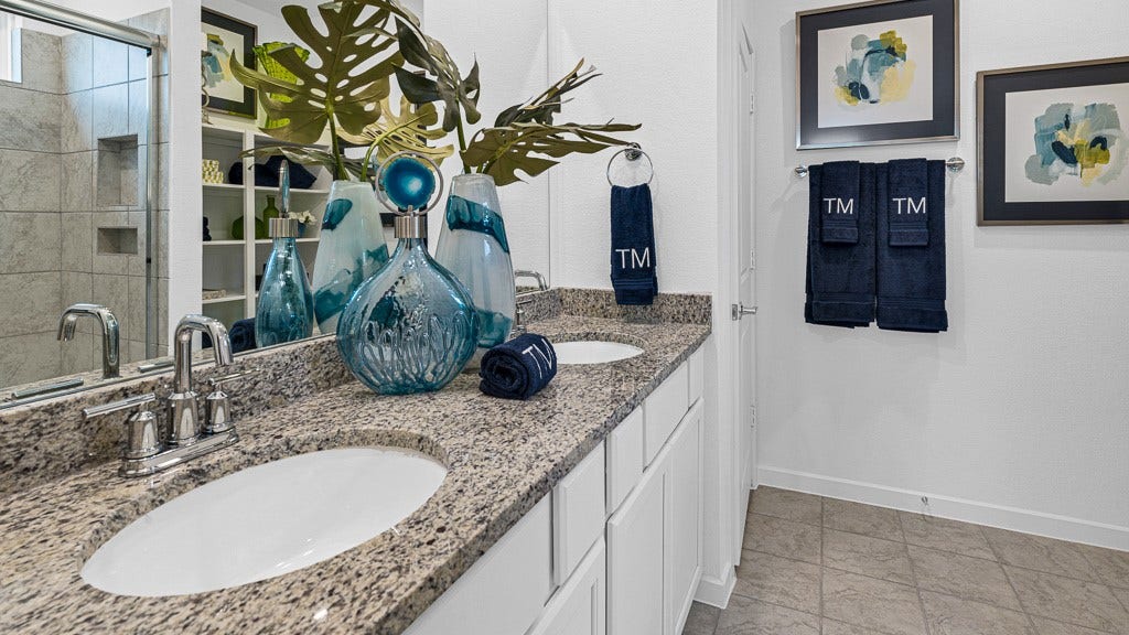 7334 Grand Mason Drive, Cypress, TX 77433 Primary ensuite bath has dual vanities with silver fixtures, modern white cabinetry, and recessed shelves for towels, storage and decor.