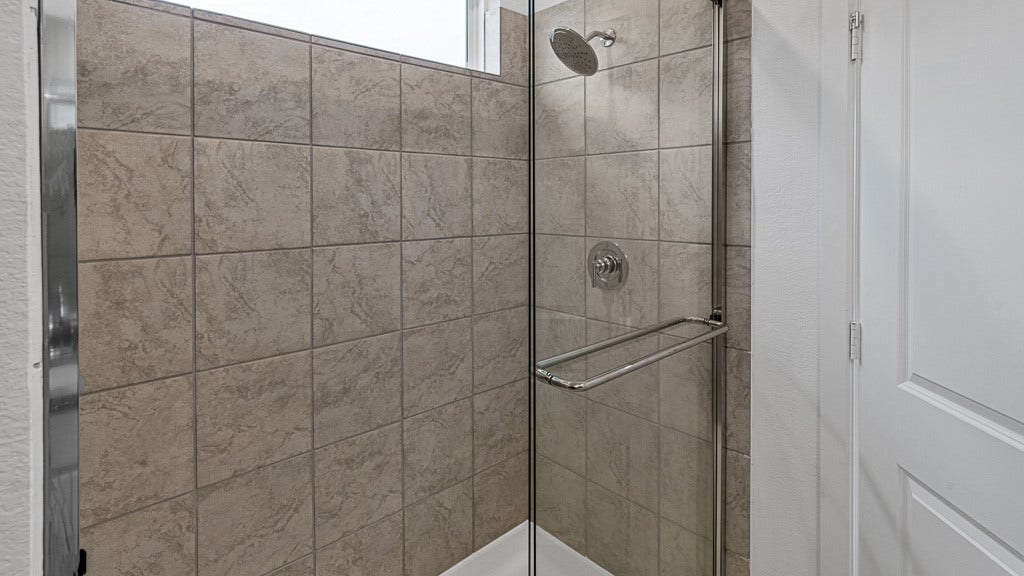 7334 Grand Mason Drive, Cypress, TX 77433 Walk-in shower has a high window and tiled walls with silver fixtures.