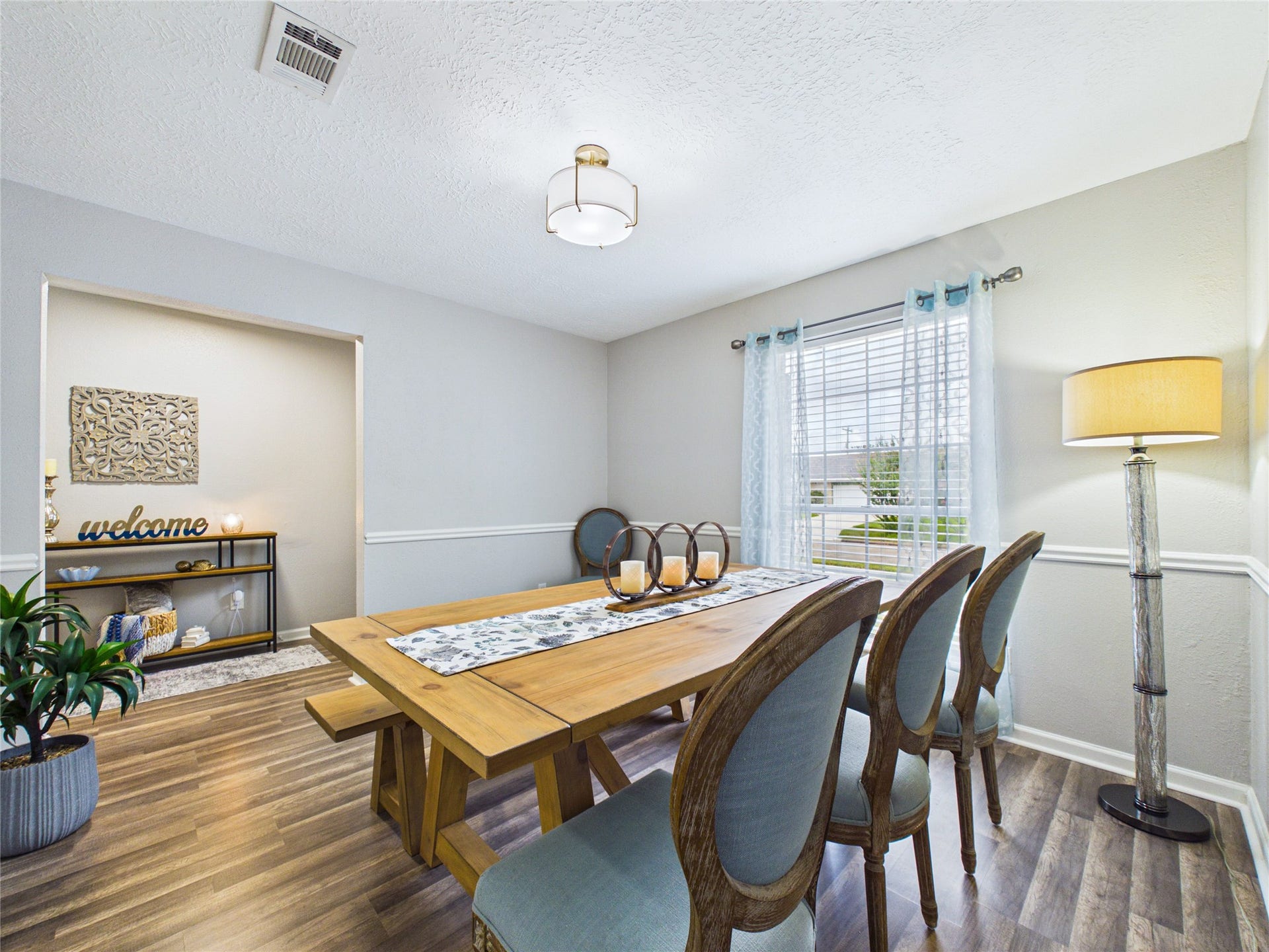 6209 Brookdale Drive, League City, TX 77573 Bright dining area with elegant flooring, a large window for natural light, and a stylish chandelier.