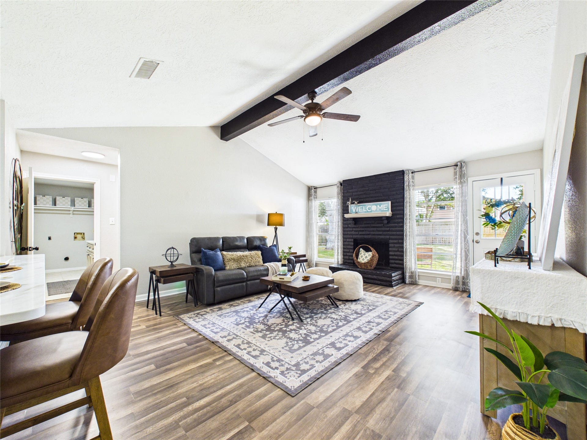 6209 Brookdale Drive, League City, TX 77573 Bright and inviting living space with vaulted ceilings, featuring a cozy seating area, a stylish black accent wall, and large windows that fill the room with natural light.