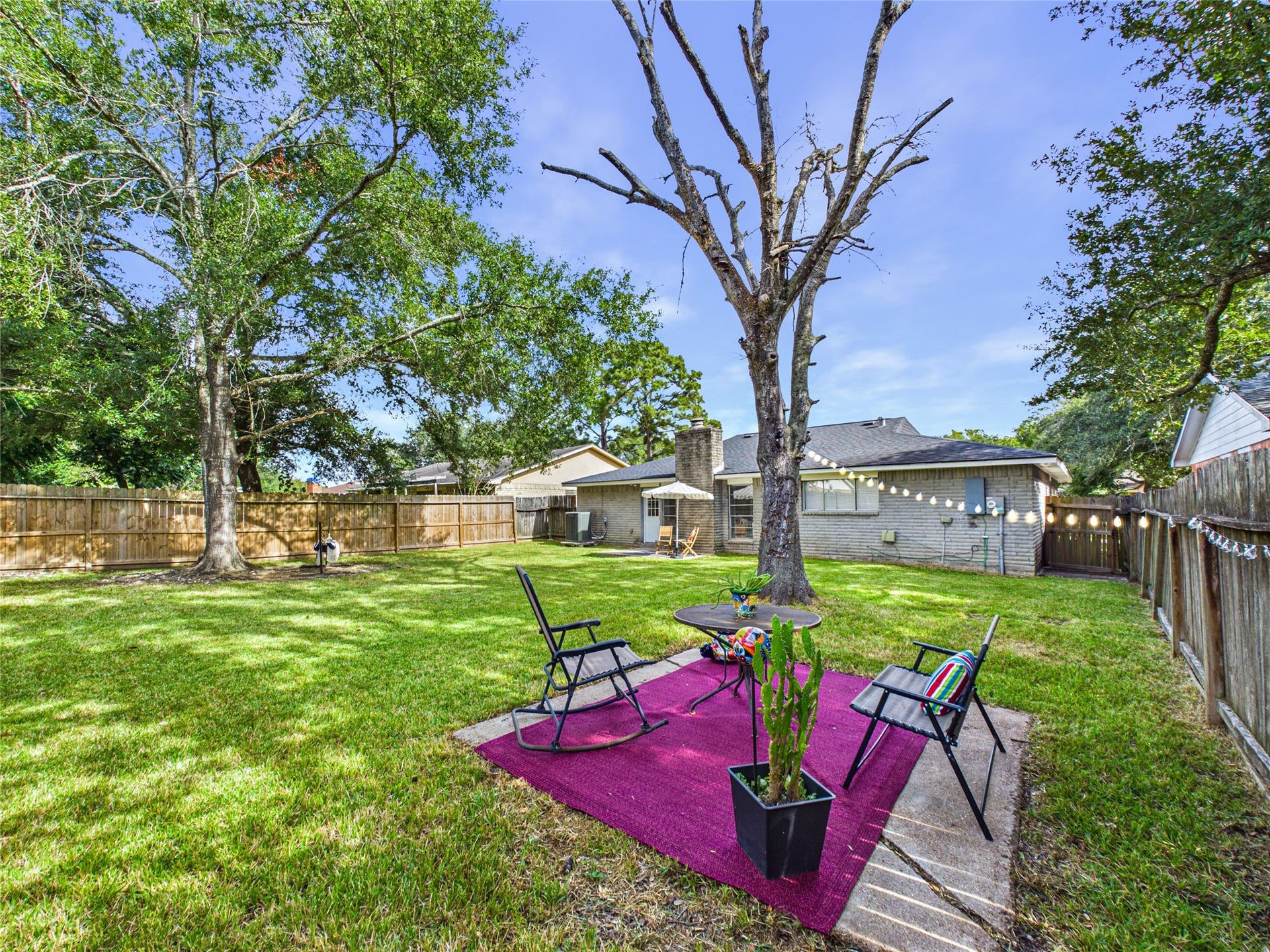 6209 Brookdale Drive, League City, TX 77573 The spacious backyard with lush green lawn, mature trees, and a cozy seating area perfect for outdoor relaxation and entertaining.