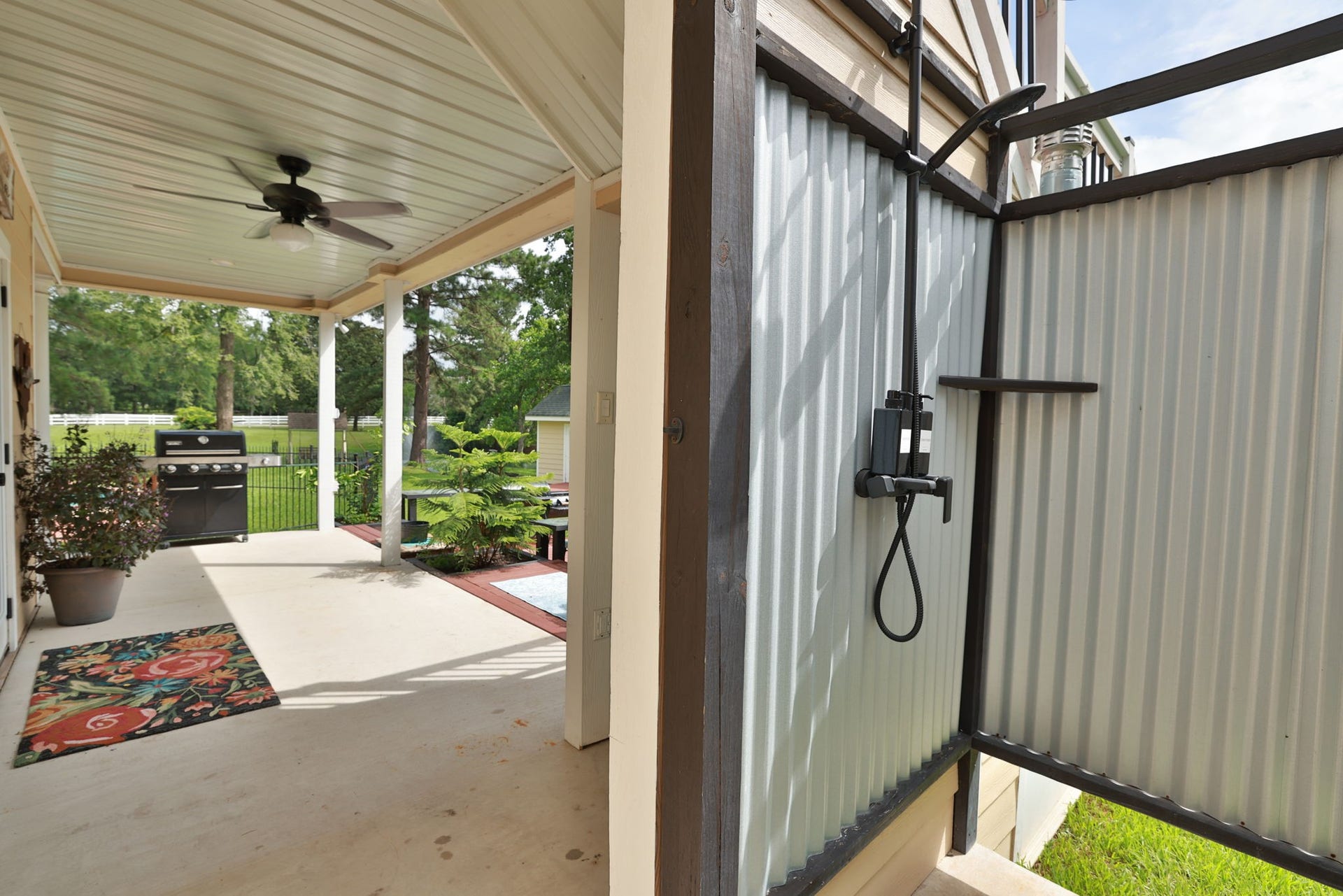 34310 High Point Drive, Magnolia, TX 77355 This photo shows a covered patio area with a ceiling fan and a convenient outdoor shower. Wonderful outdoor living space at it's finest!