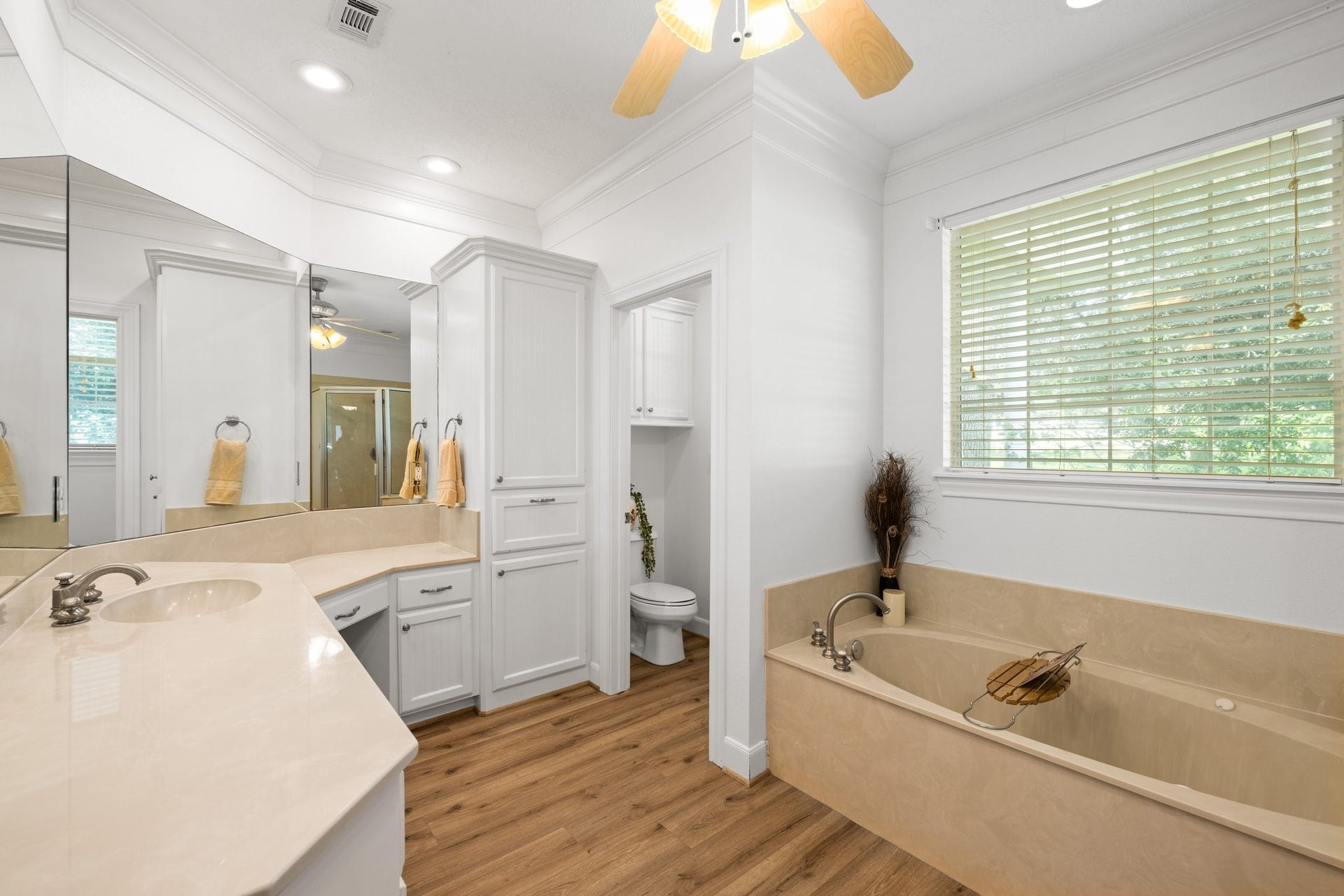 34310 High Point Drive, Magnolia, TX 77355 This elegant primary bathroom boasts a spacious design with a large vanity, ample storage, a relaxing tub, and warm vinyl plank flooringperfect for unwinding after a long day.