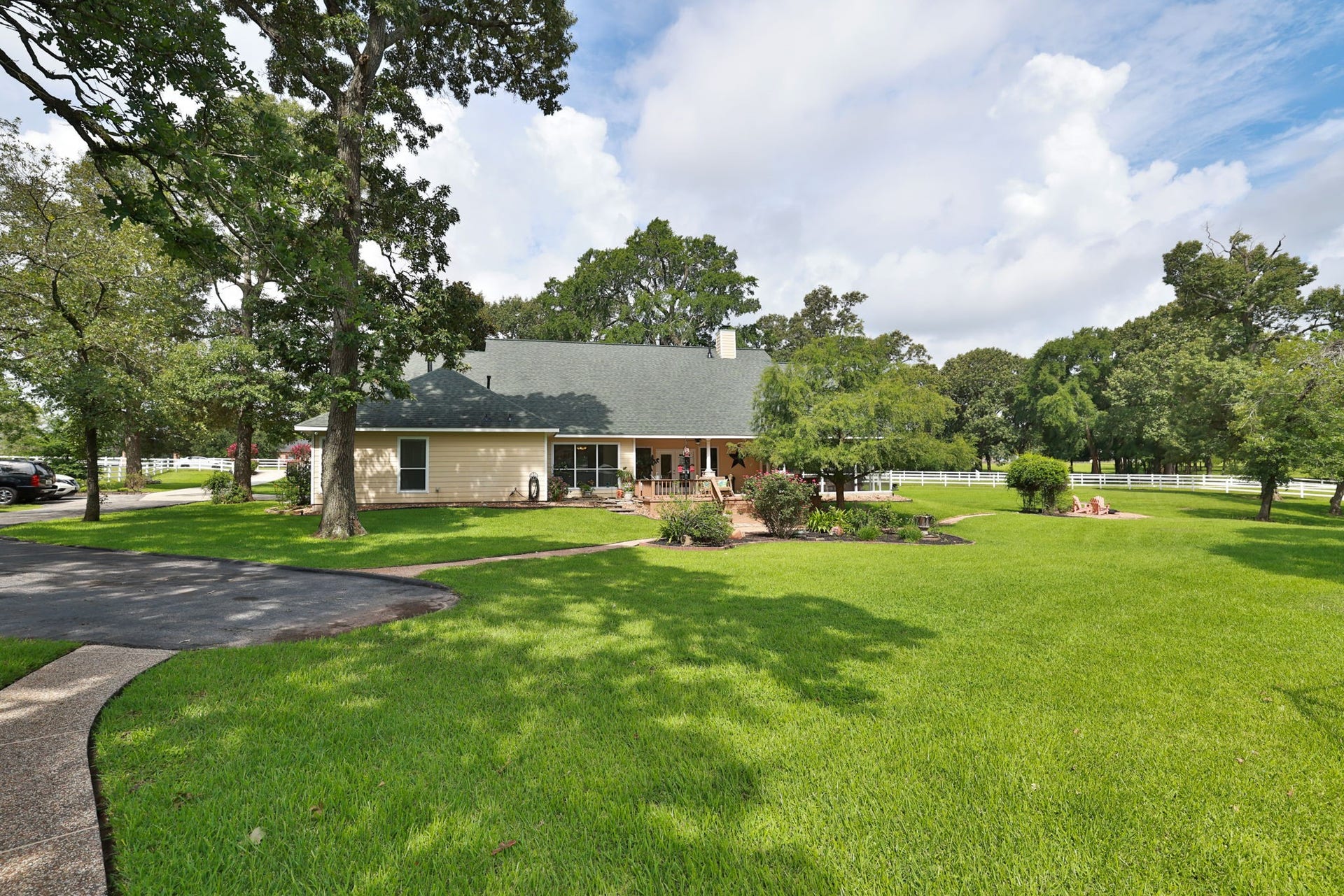 34310 High Point Drive, Magnolia, TX 77355 Charming home with a large, manicured lawn and mature trees. It features a spacious driveway, a welcoming porch, and is surrounded by lush greenery, perfect for privacy and outdoor activities.