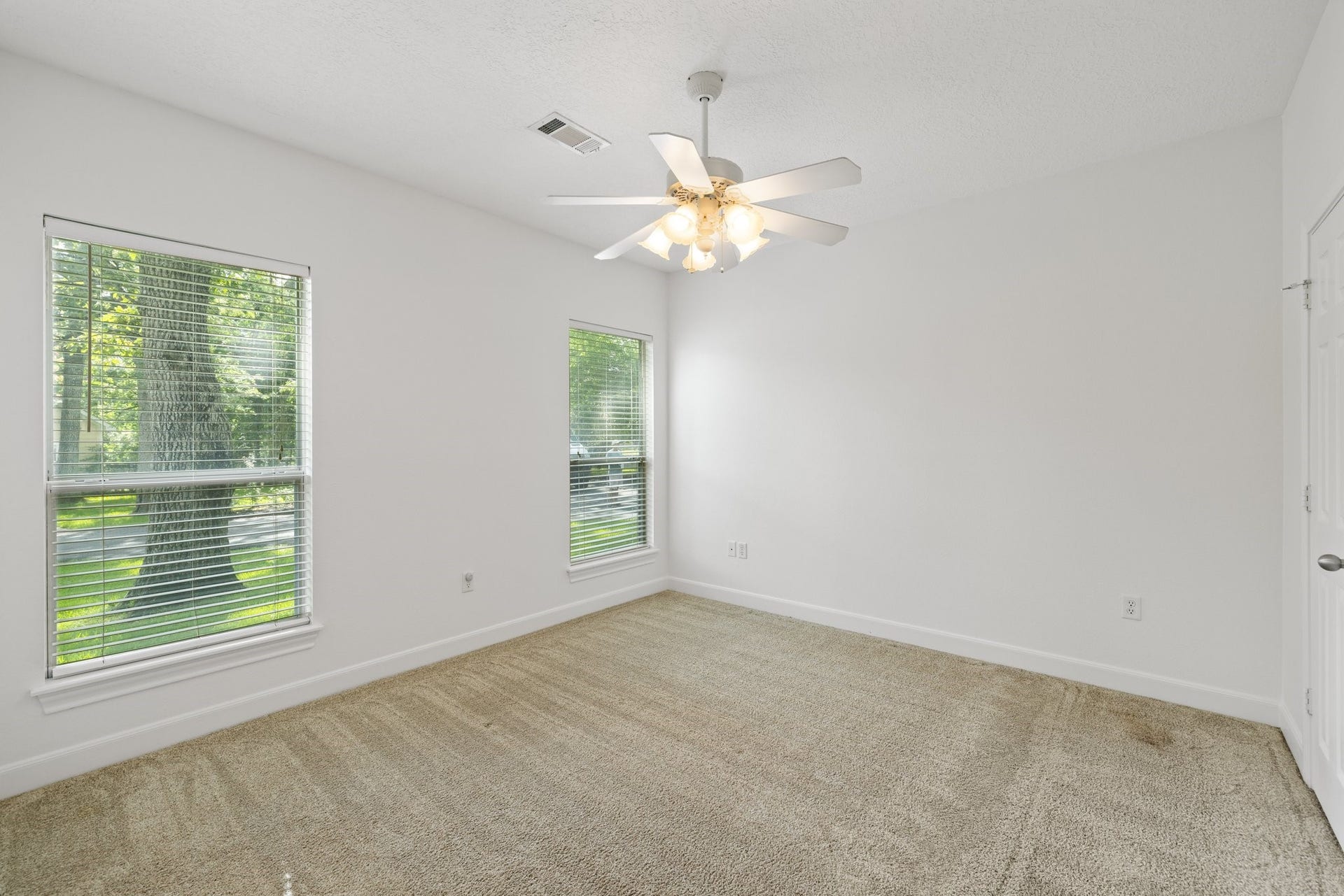 34310 High Point Drive, Magnolia, TX 77355 Bright secondary bedroom with ensuite bath, featuring new carpet and a ceiling fan.