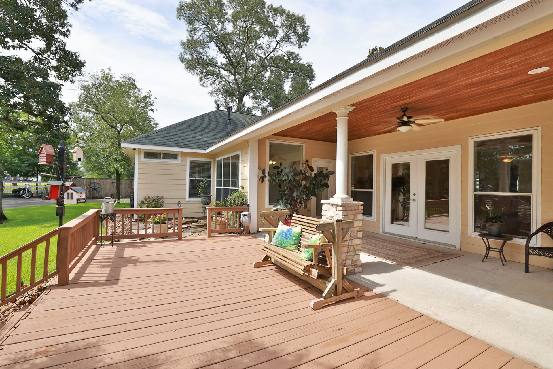 34310 High Point Drive, Magnolia, TX 77355 This photo showcases a spacious wooden deck with a cozy covered patio area. The patio features ceiling fans, ample seating, and large windows, offering a welcoming outdoor space with a view of the lush backyard.