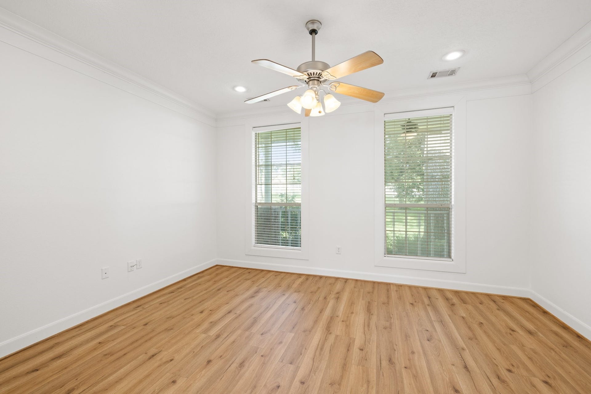 34310 High Point Drive, Magnolia, TX 77355 Expansive primary bedroom with elegant vinyl plank flooring, a ceiling fan, and serene outdoor views.