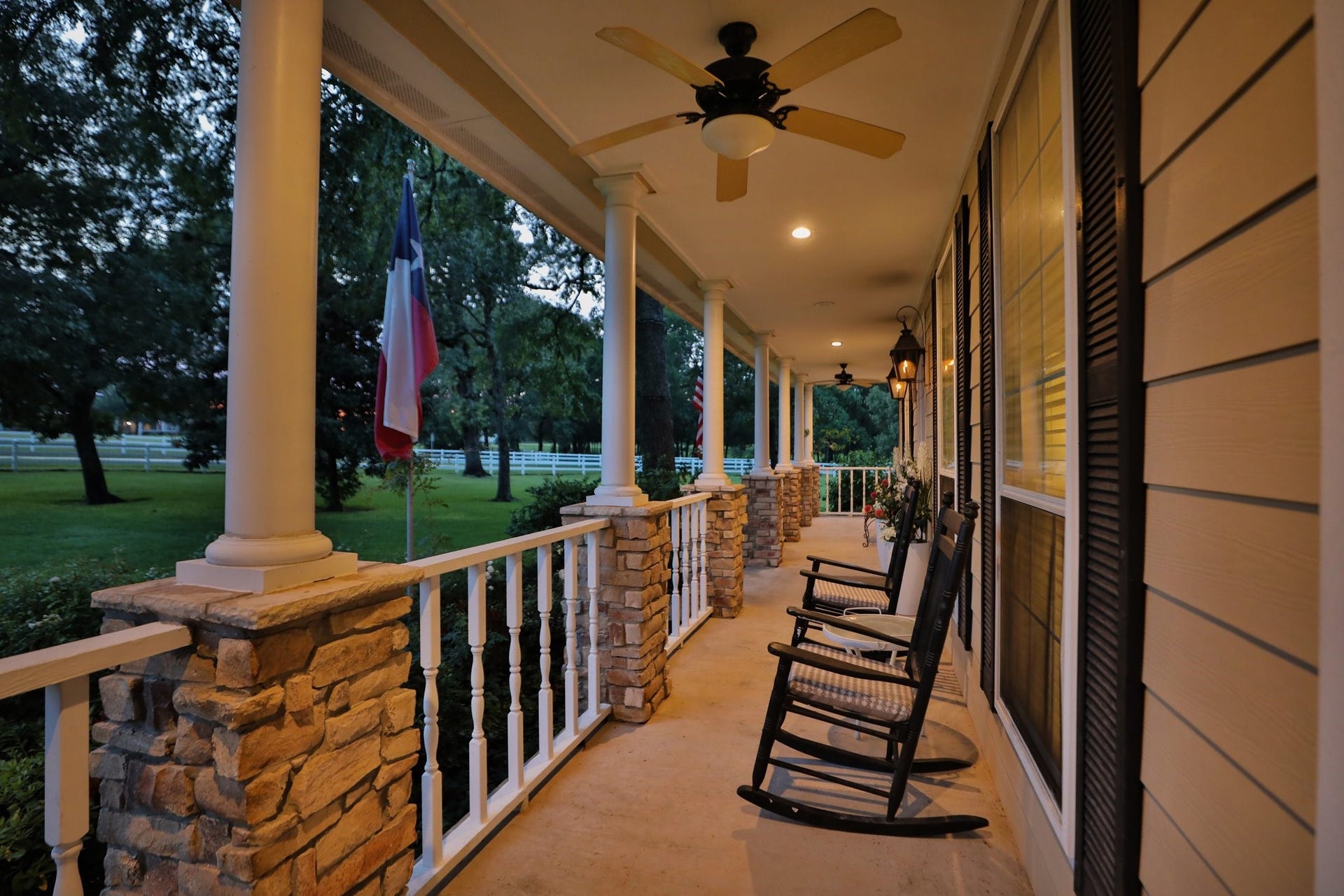 34310 High Point Drive, Magnolia, TX 77355 This inviting home features a spacious front porch with stone pillars, ceiling fans, perfect for relaxing. Surrounded by lush greenery it offers a serene setting for outdoor enjoyment.