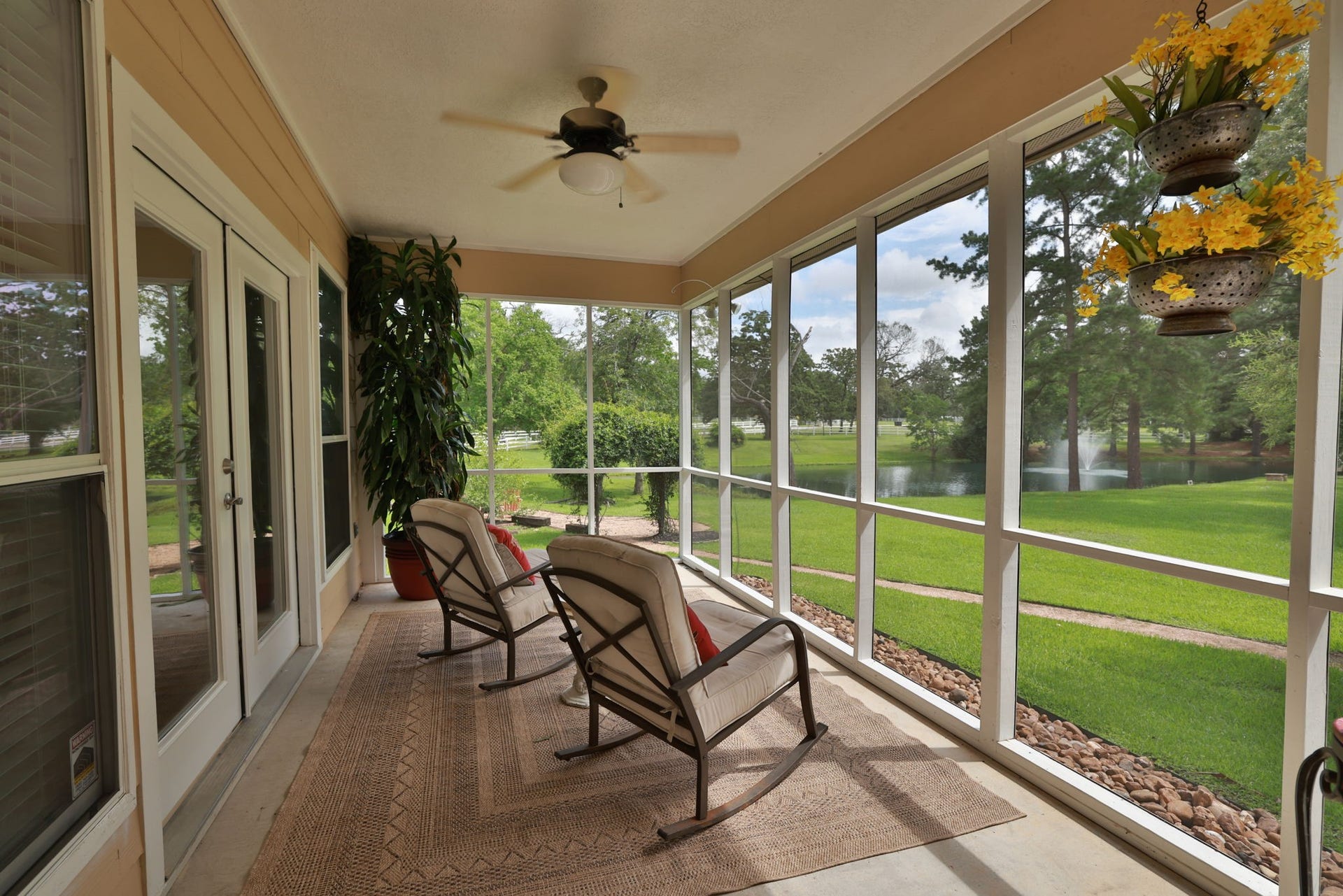 34310 High Point Drive, Magnolia, TX 77355 This photo showcases a serene screened-in porch room for your own cozy seating, overlooking a lush green lawn and a tranquil pond. Perfect for relaxation and enjoying nature.