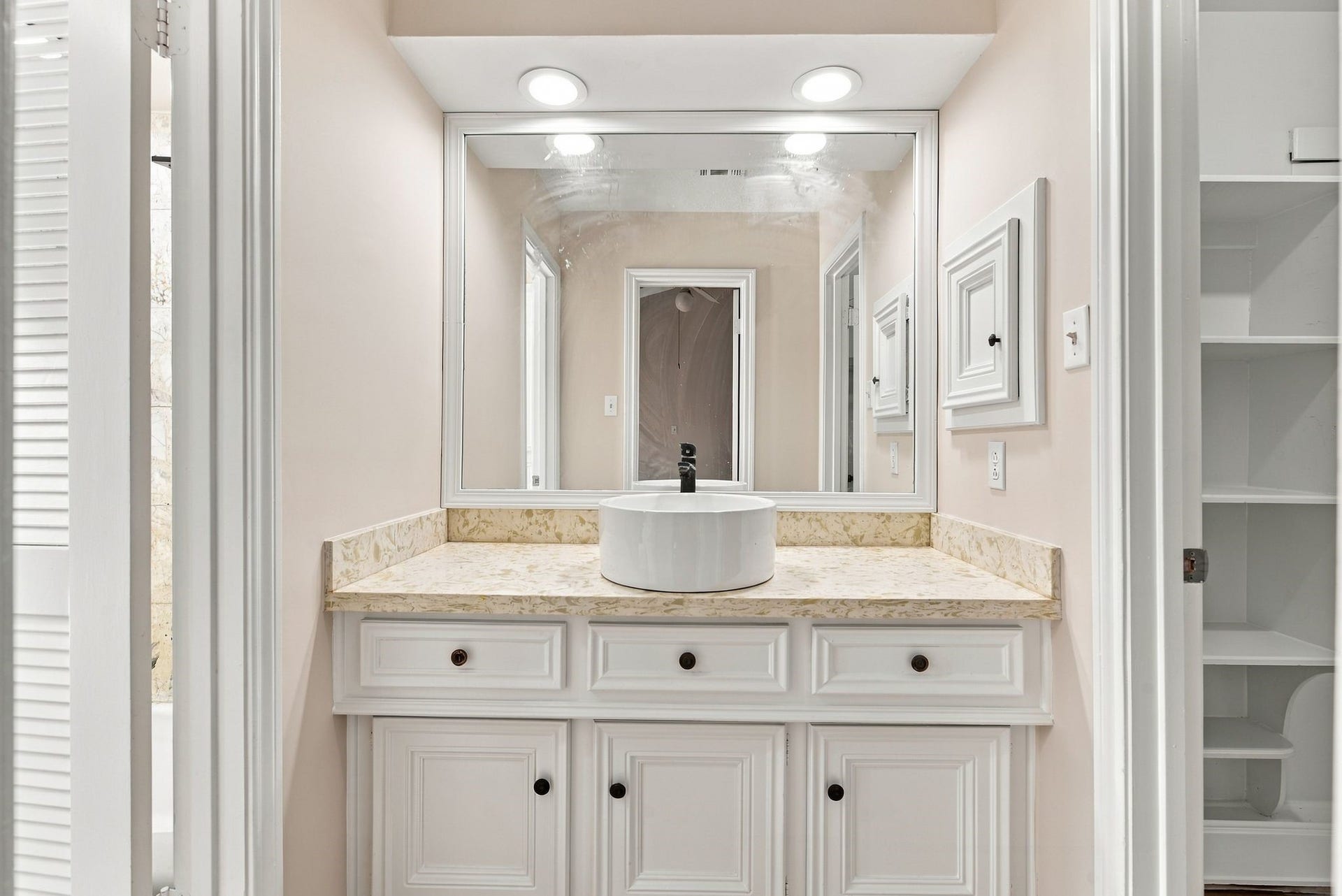 Primary ensuite bathroom featuring a double-sink vanity, generous countertop space, and built-in storage.
