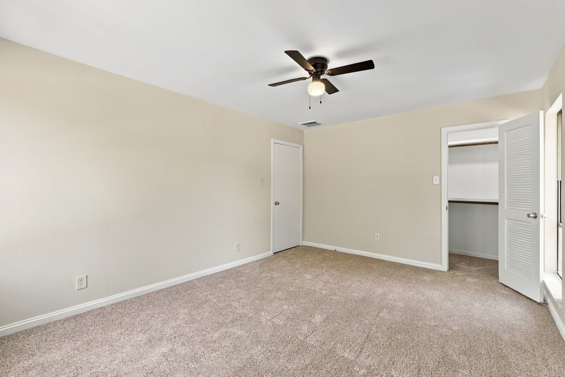 Another view of the upstairs bedroom showcasing its generous layout, neutral finishes, and closet access.
