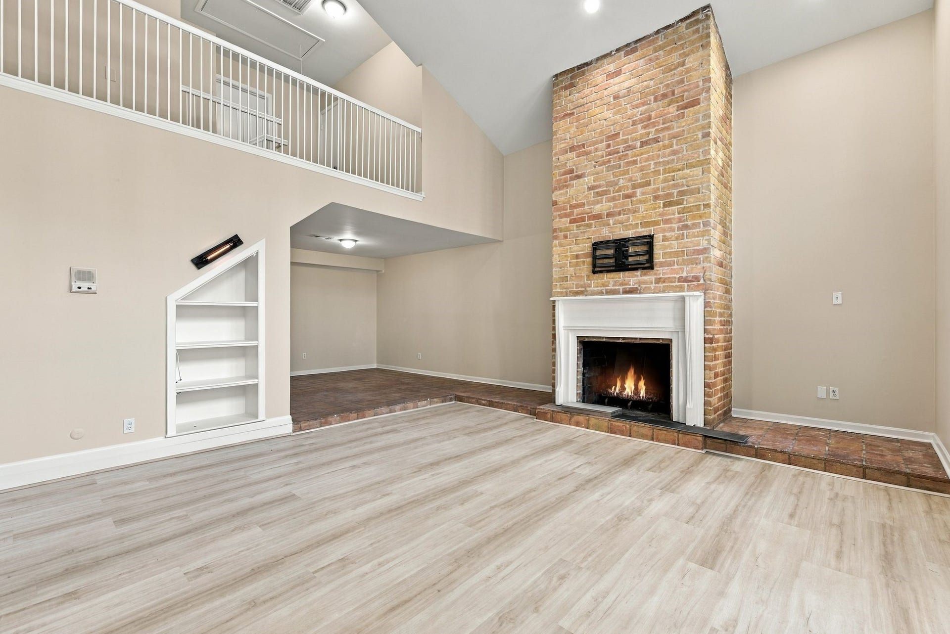 Floor-to-ceiling brick fireplace anchors this impressive living space with vaulted ceilings and an open layout.