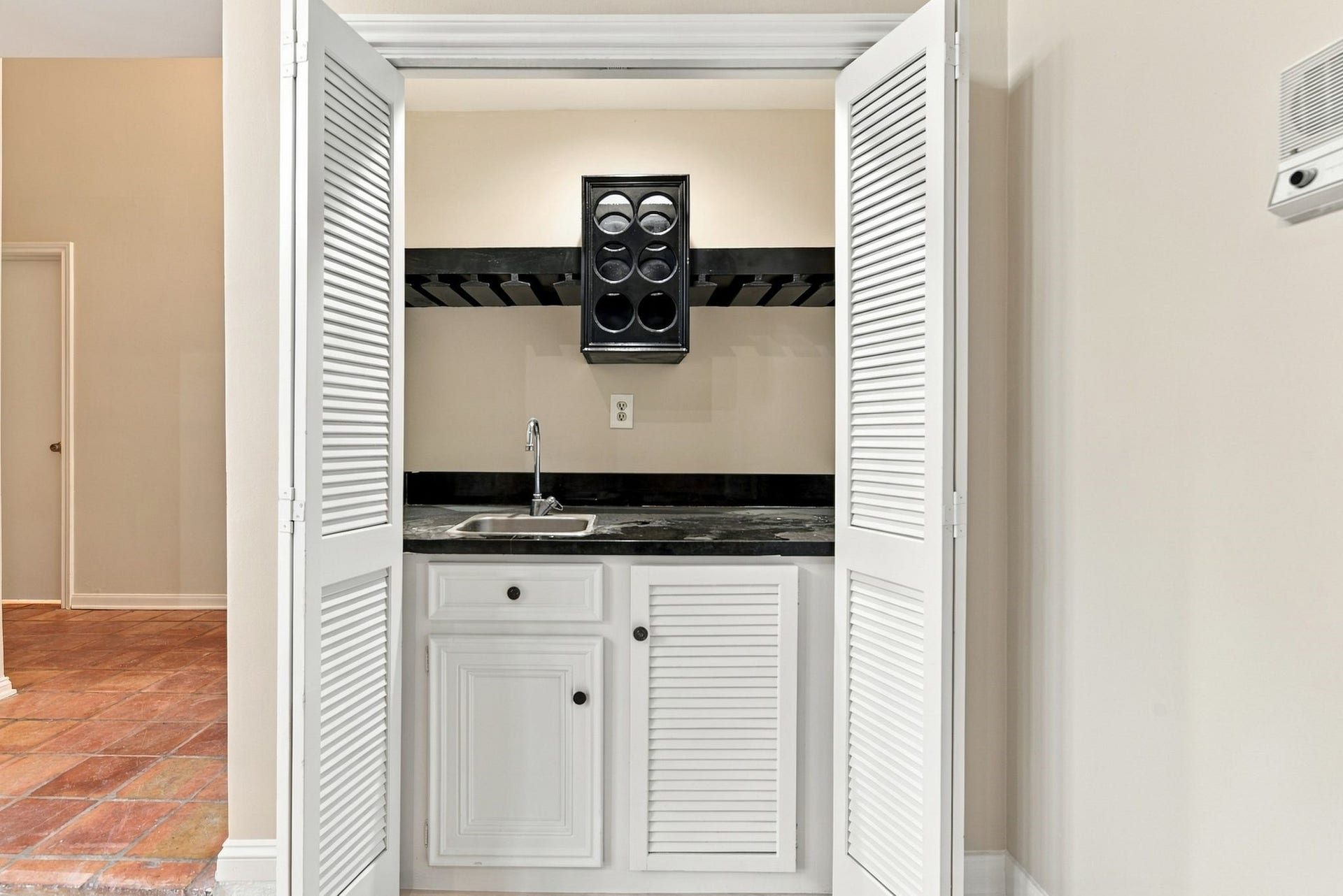 Convenient built-in wet bar with sink, cabinetry, wine bottle/glass storage and countertop space, located just off the main living area.