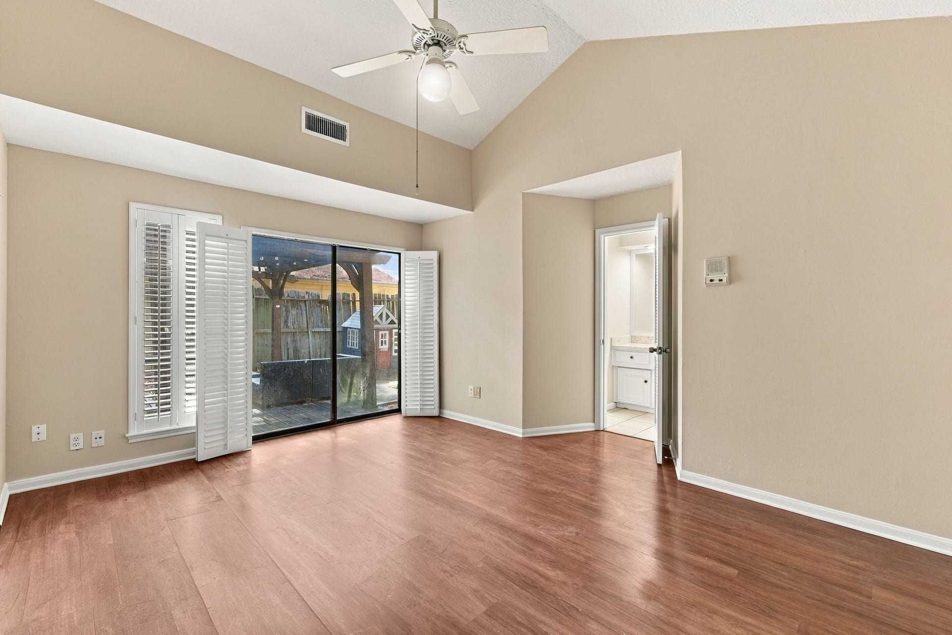 Unstaged view of the primary suite showcasing the sliding glass doors, natural light, and access to the outdoor area.