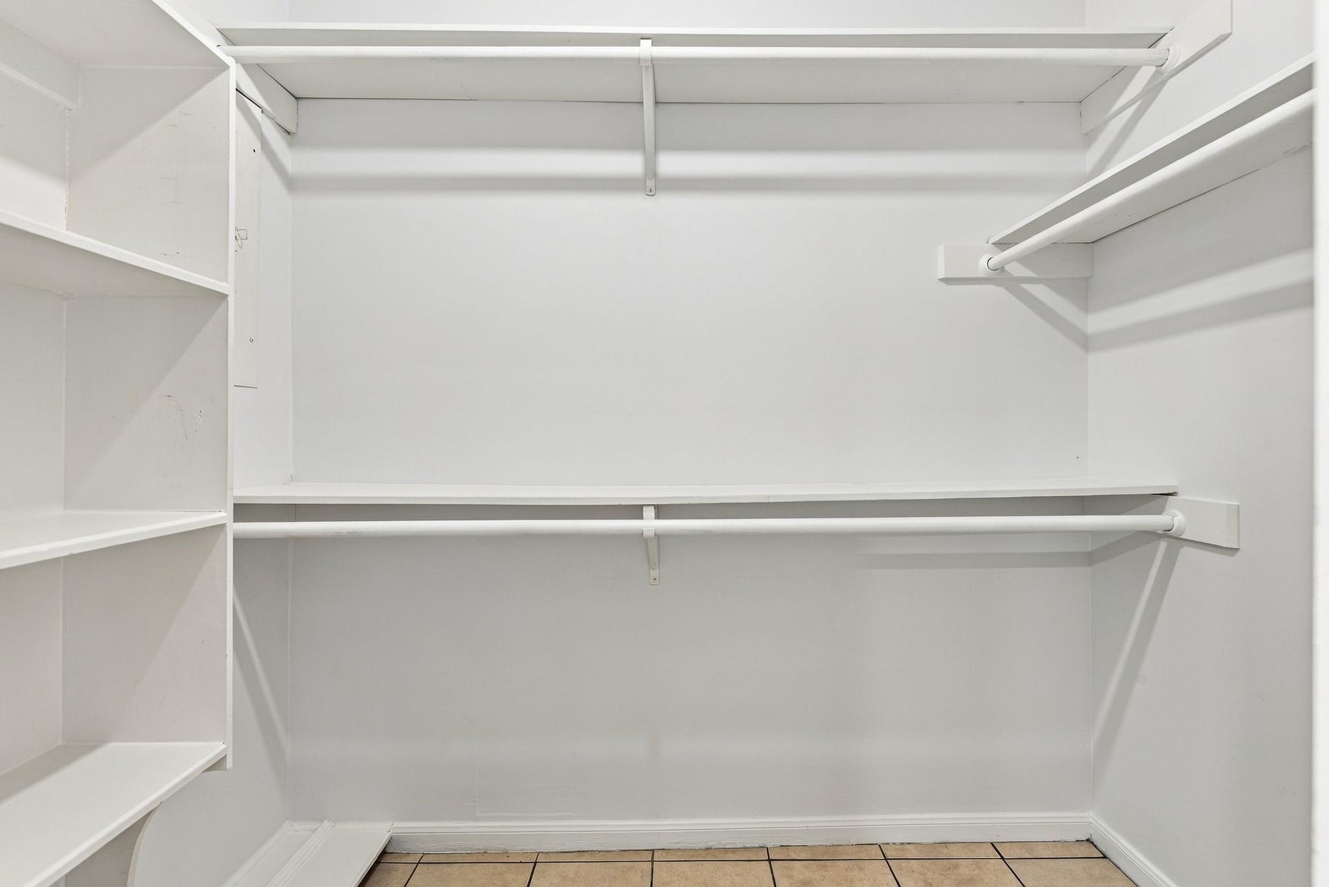Spacious primary walk-in closet featuring built-in shelving and hanging storage.