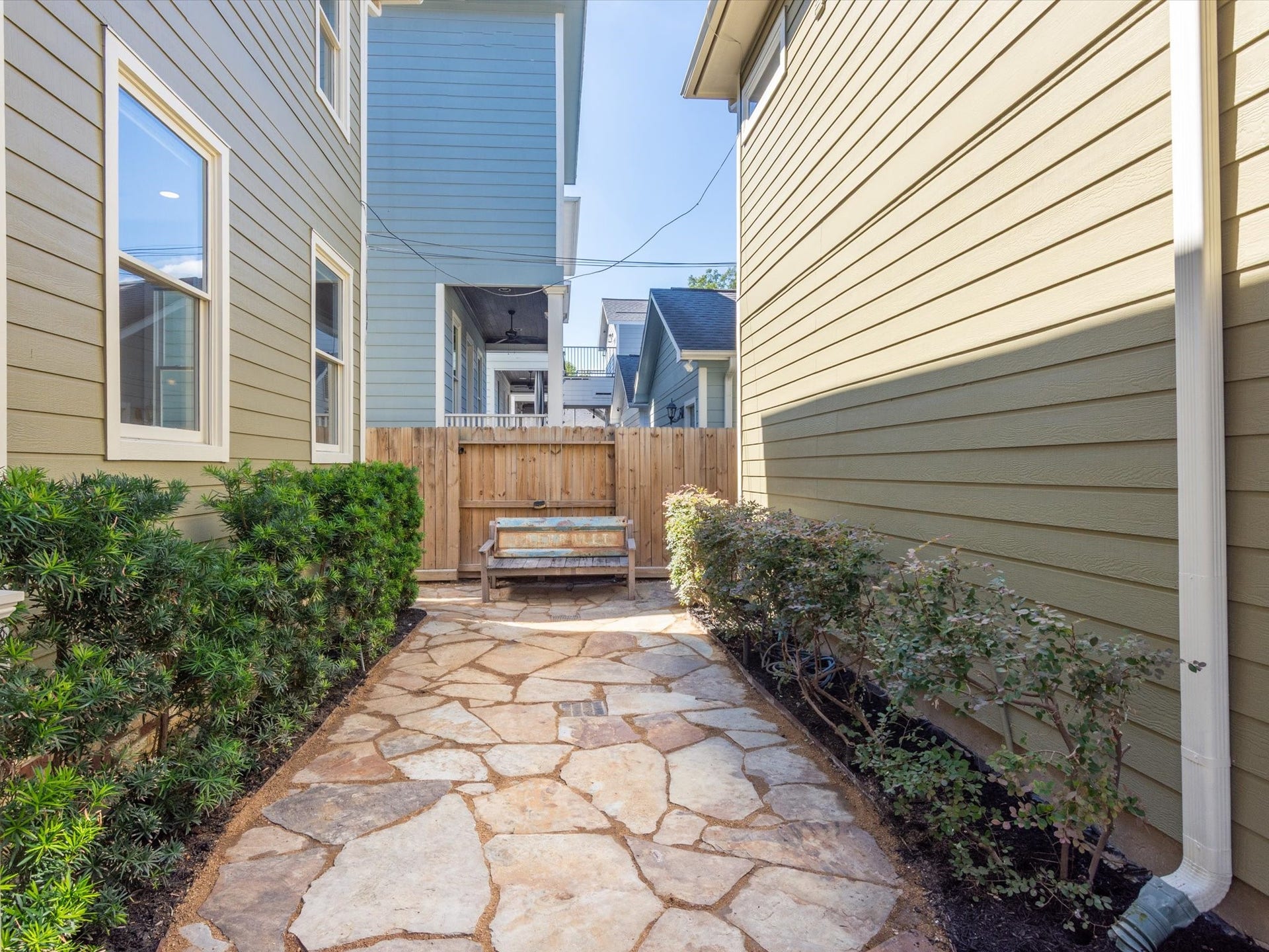 837 E 27th Street, Houston, TX 77009 Charming stone pathway lined with lush greenery leads to a cozy wooden bench, offering a serene outdoor retreat.