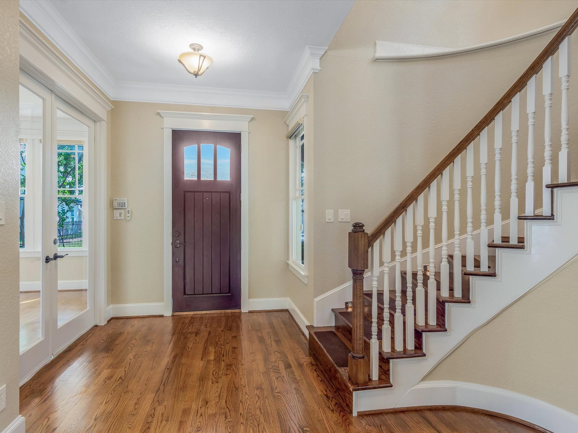837 E 27th Street, Houston, TX 77009 Inviting foyer with rich solid oak wood floors, elegant staircase, and abundant natural light, seamlessly connecting to the home office through double French doors.