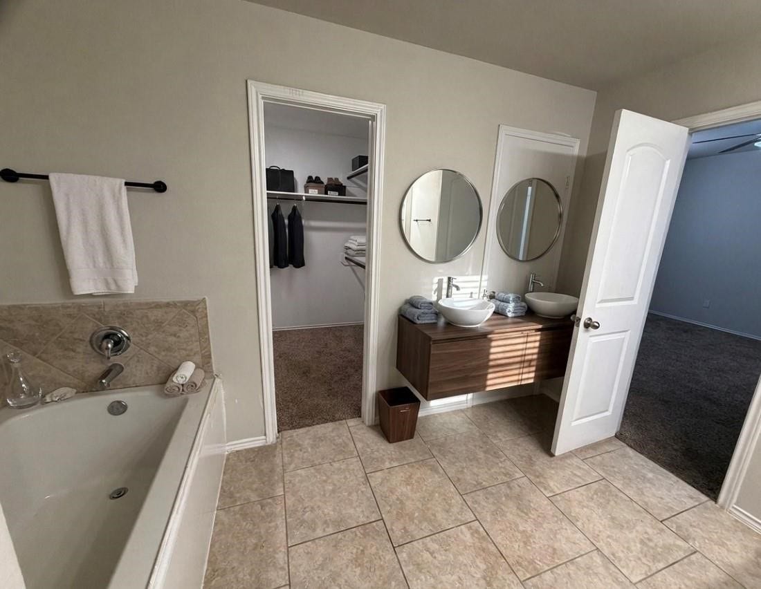 Experience luxury in this virtually staged primary bath featuring a sleek doubl, elegant tile flooring, and a spacious tub.e vanity