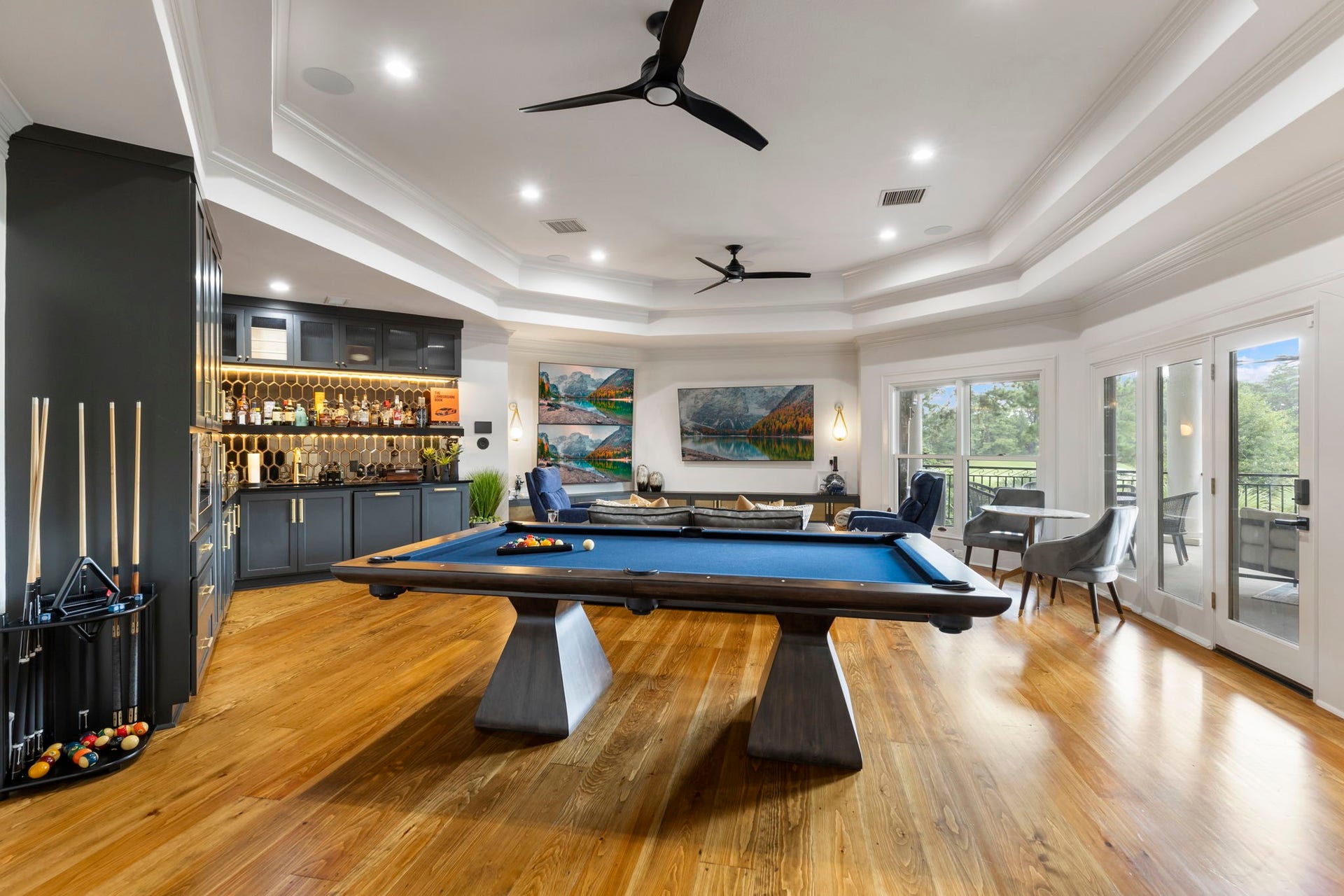 Steps away, an incredible game room presents beautifully with wood flooring, custom built in storage and display cabinetry, wet sink, microwave, fridge and opens to a spacious balcony.