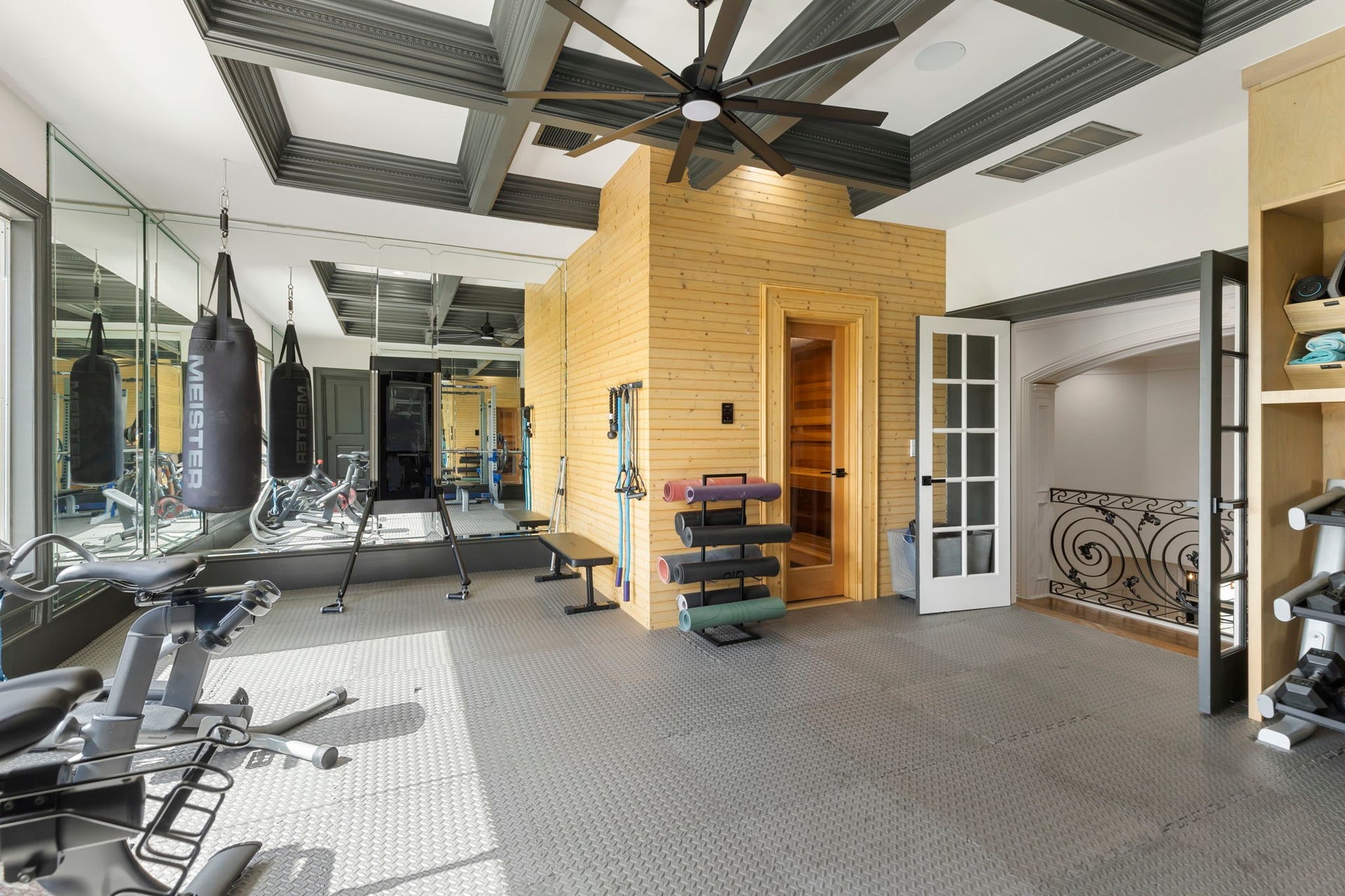 This home gym is a true wellness retreat, featuring a private sauna, mirrored workout wall, and rubber-matted flooring designed for serious training in style.