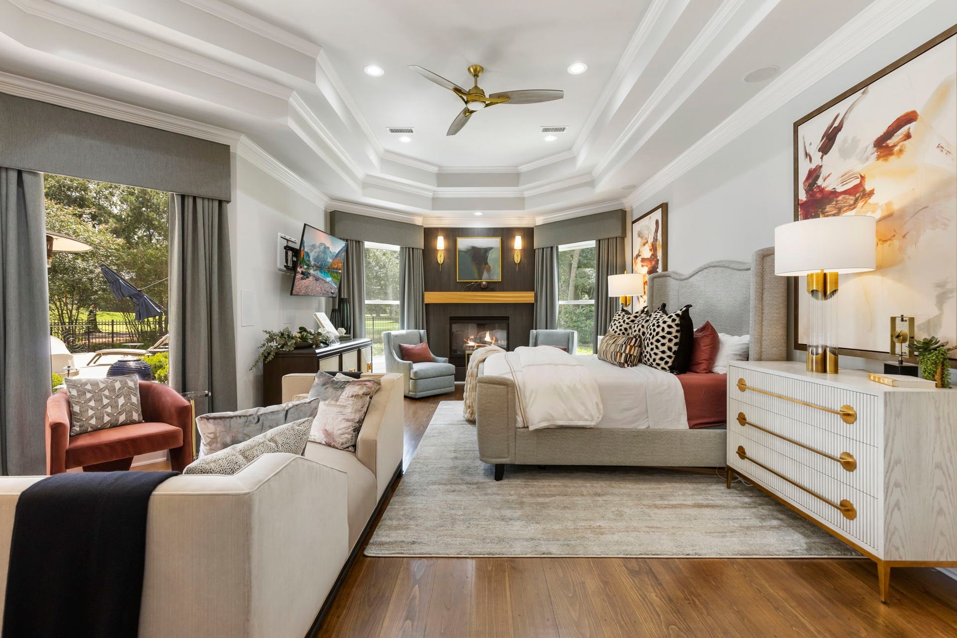 Primary Suite: Spacious primary suite highlights a tray ceiling, sitting area, cozy fireplace and walls of windows framing views of the backyard & pool.