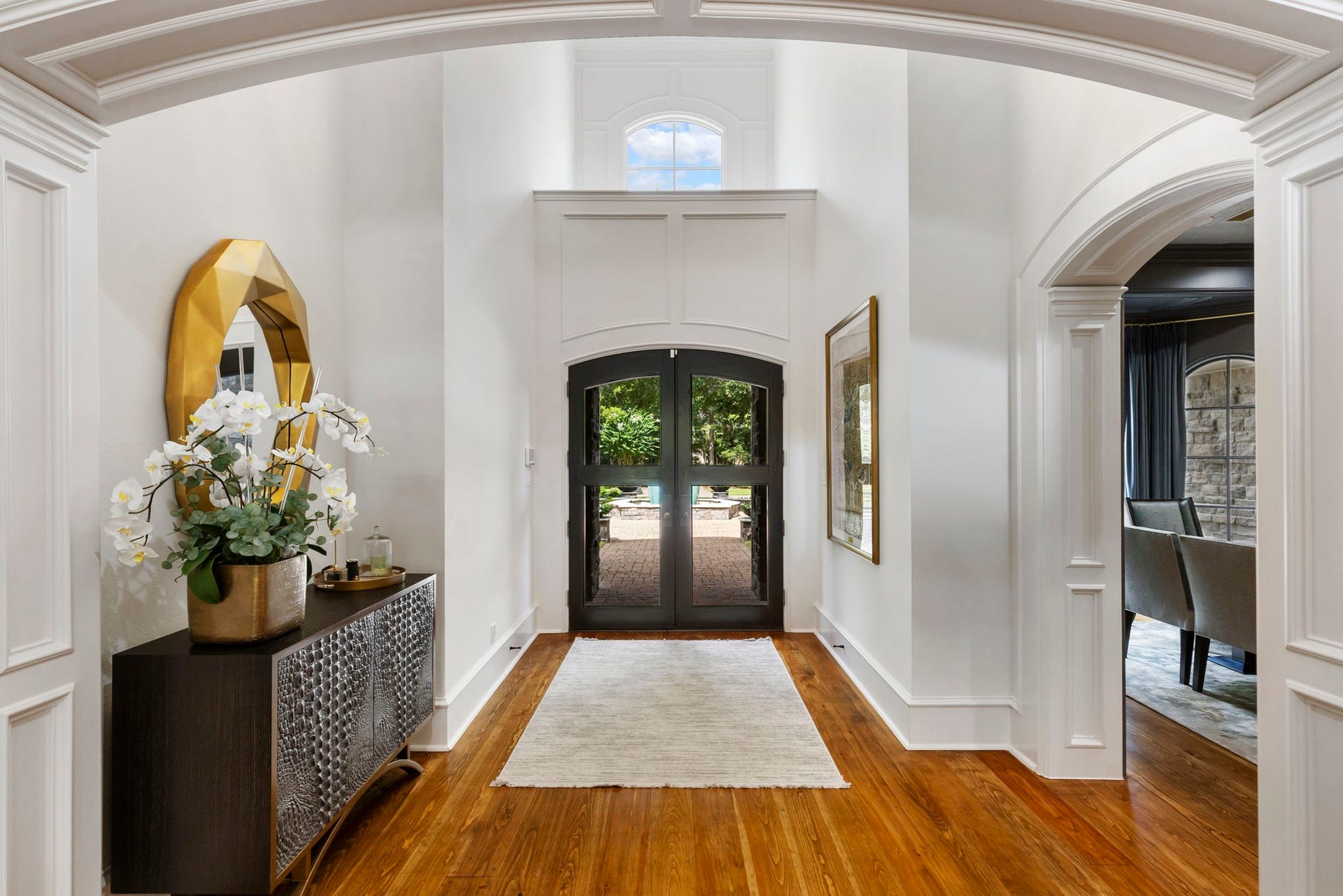 Step inside to a soaring 2 story entry framed by an arched transom window & double iron-and-glass front doors. Stunning wood floors flow throughout the first floor.