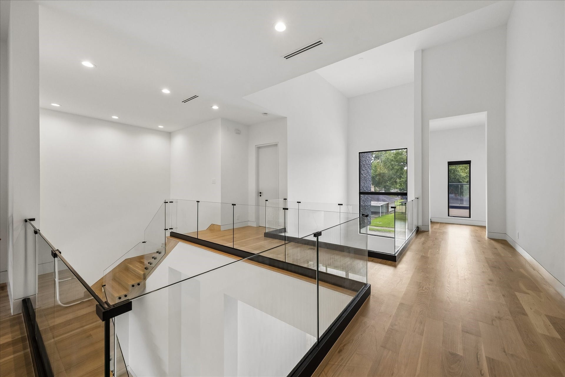 The second floor landing is open and  bright with sleek glass railings and hardwood floors providing access to three bedrooms and the laundry room.