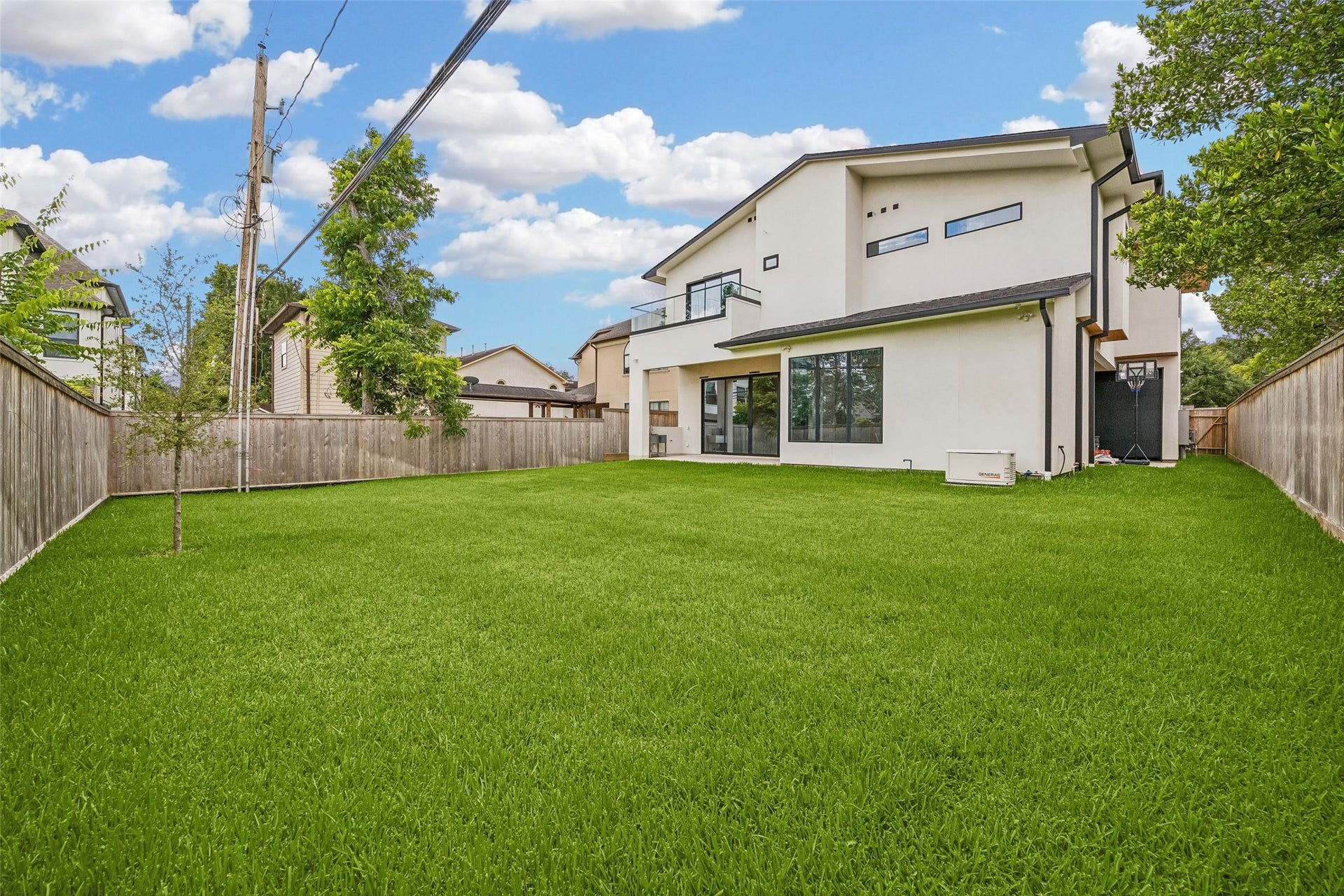 Clean white exterior, large windows, and a spacious, fenced in backyard. The property offers ample outdoor space, ideal for entertaining and plenty of room for a future pool.