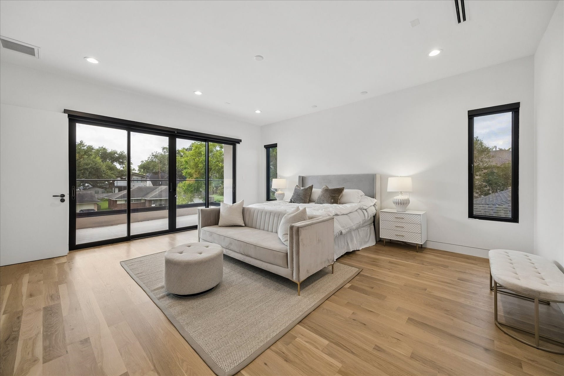 This spacious primary suite has access to a private balcony with scenic views of the neighborhood. The hardwood floors add warmth and sophistication to the space.