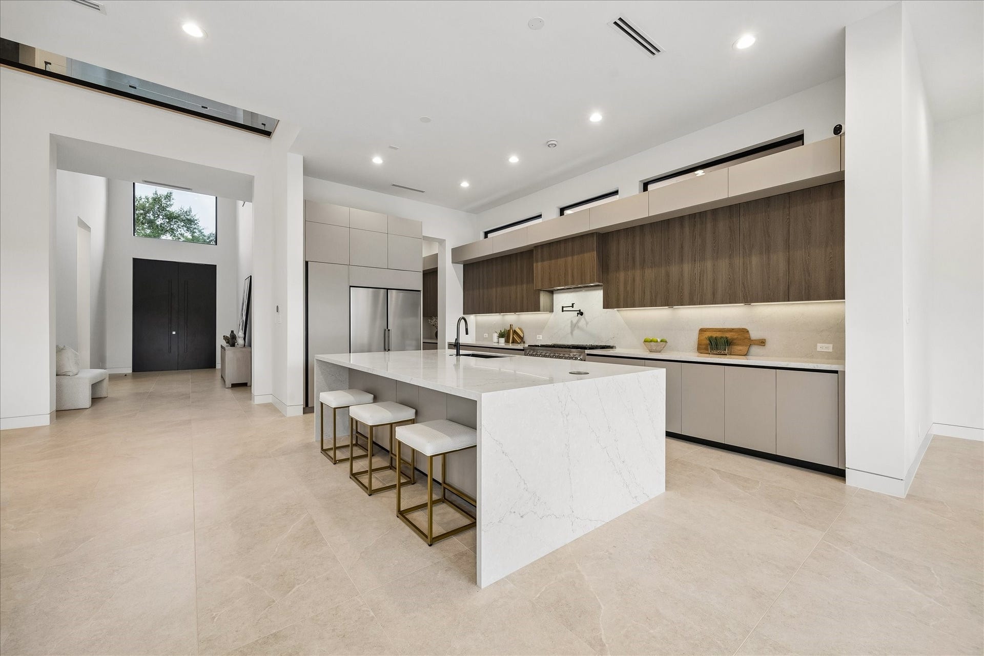 The kitchen features a spacious island with seating, sleek cabinetry, and high-end appliances. The open layout and large windows provide plenty of natural light, creating an airy and inviting atmosphere.