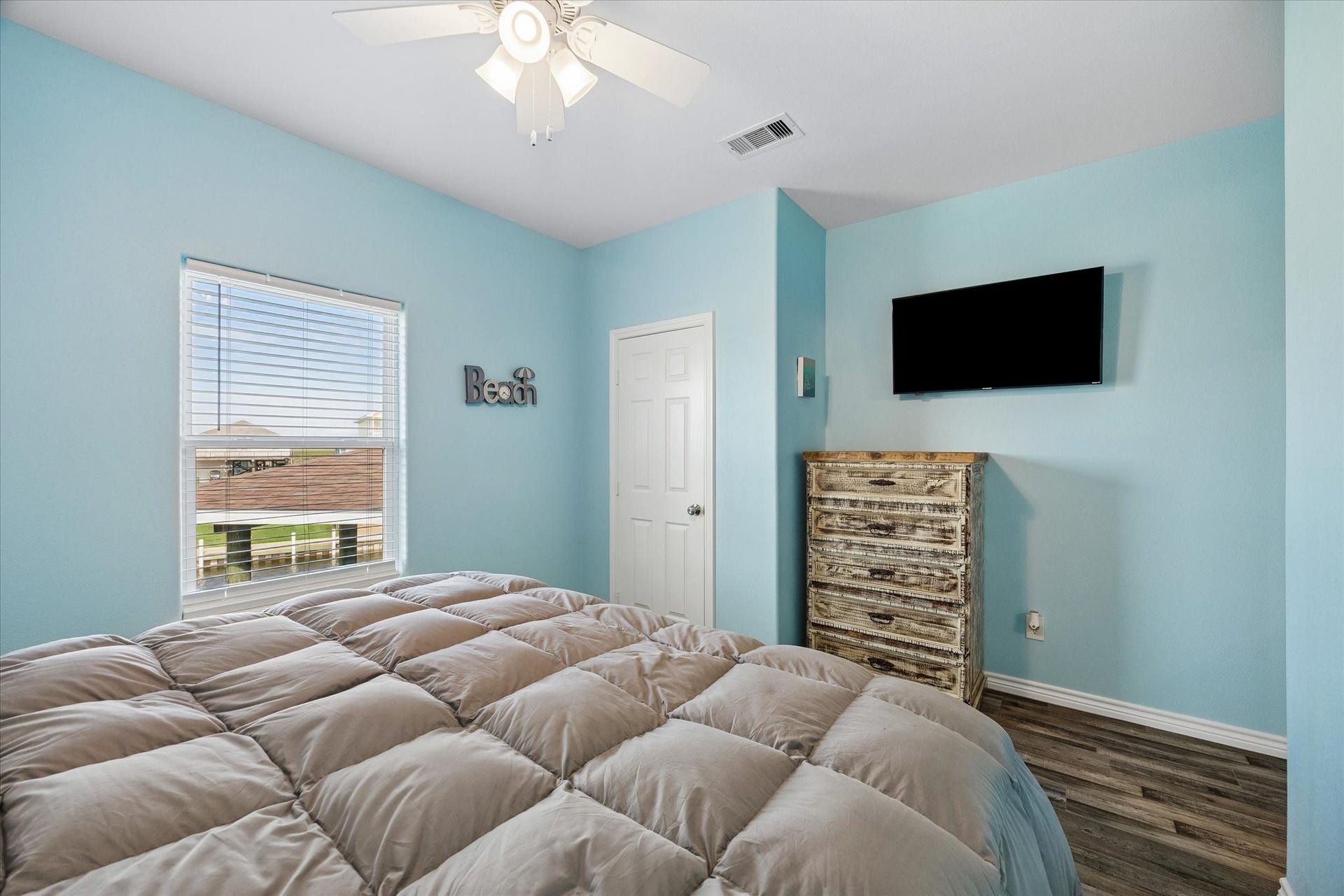 161 Four Master Road, Freeport, TX 77541 Cozy bedroom with soft blue walls, featuring a ceiling fan, complemented by a large window for natural light.
