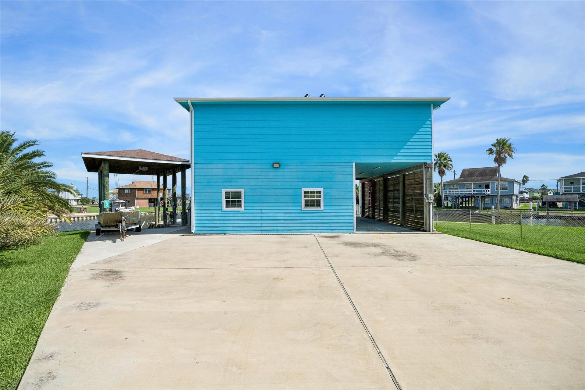 161 Four Master Road, Freeport, TX 77541 A vibrant blue waterfront home with a spacious driveway, inviting covered patio, and direct canal accessperfect for boating enthusiasts.
