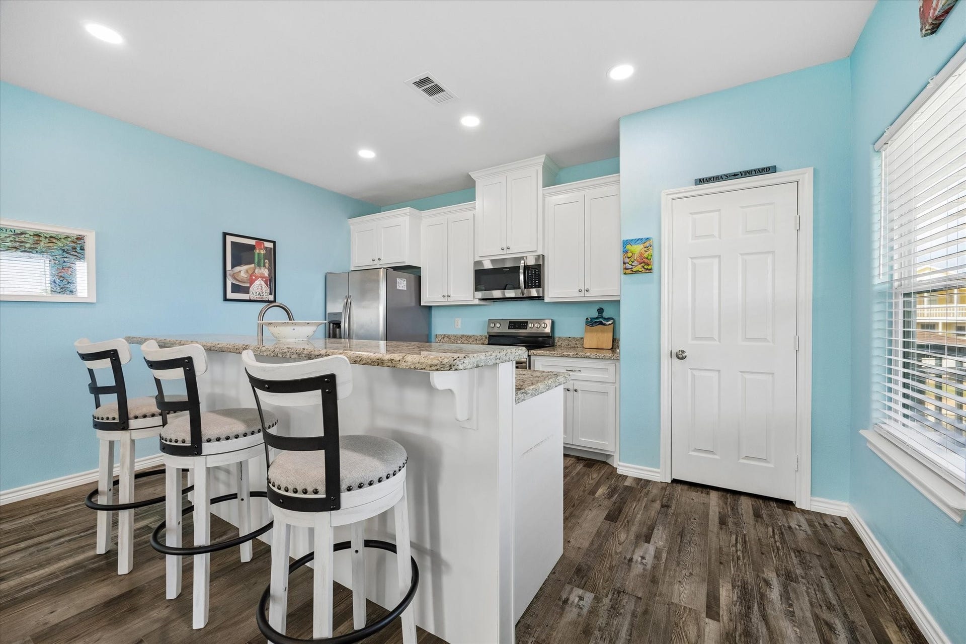 161 Four Master Road, Freeport, TX 77541 A bright and inviting kitchen with sleek white cabinetry, granite countertops, and a cozy breakfast bar featuring stylish seating.
