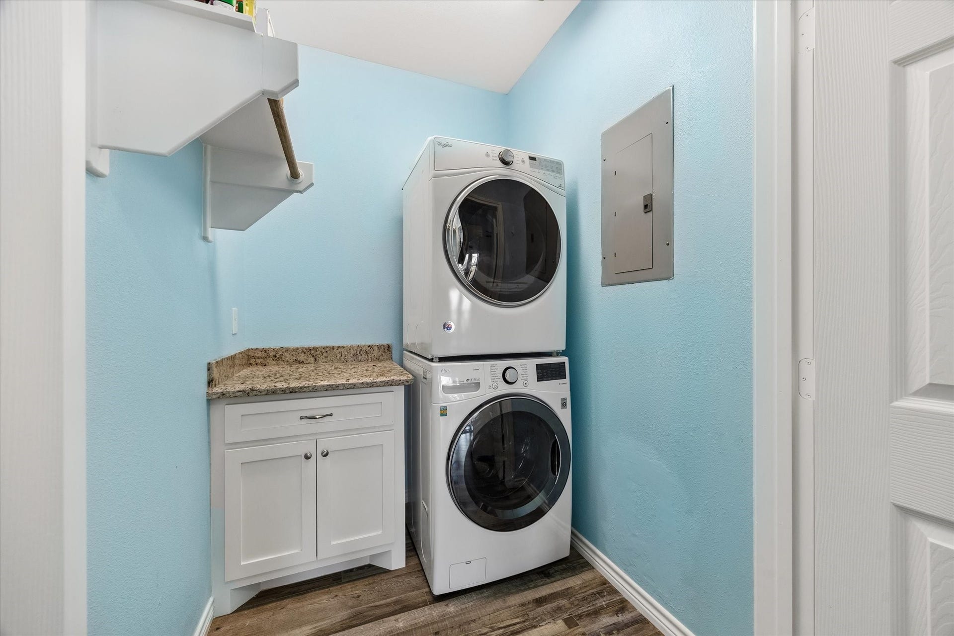 161 Four Master Road, Freeport, TX 77541 Bright and efficient laundry room featuring a stacked washer and dryer, sleek granite countertop, and ample storage with a modern cabinet and shelving.