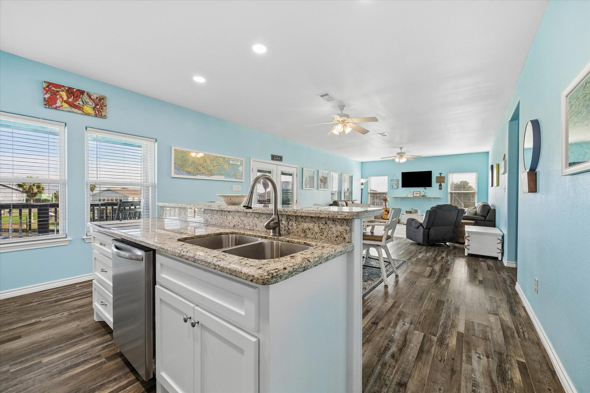 161 Four Master Road, Freeport, TX 77541 Bright and spacious open-concept living area with stylish wood flooring, modern kitchen featuring granite countertops, and ample natural light from large windows.
