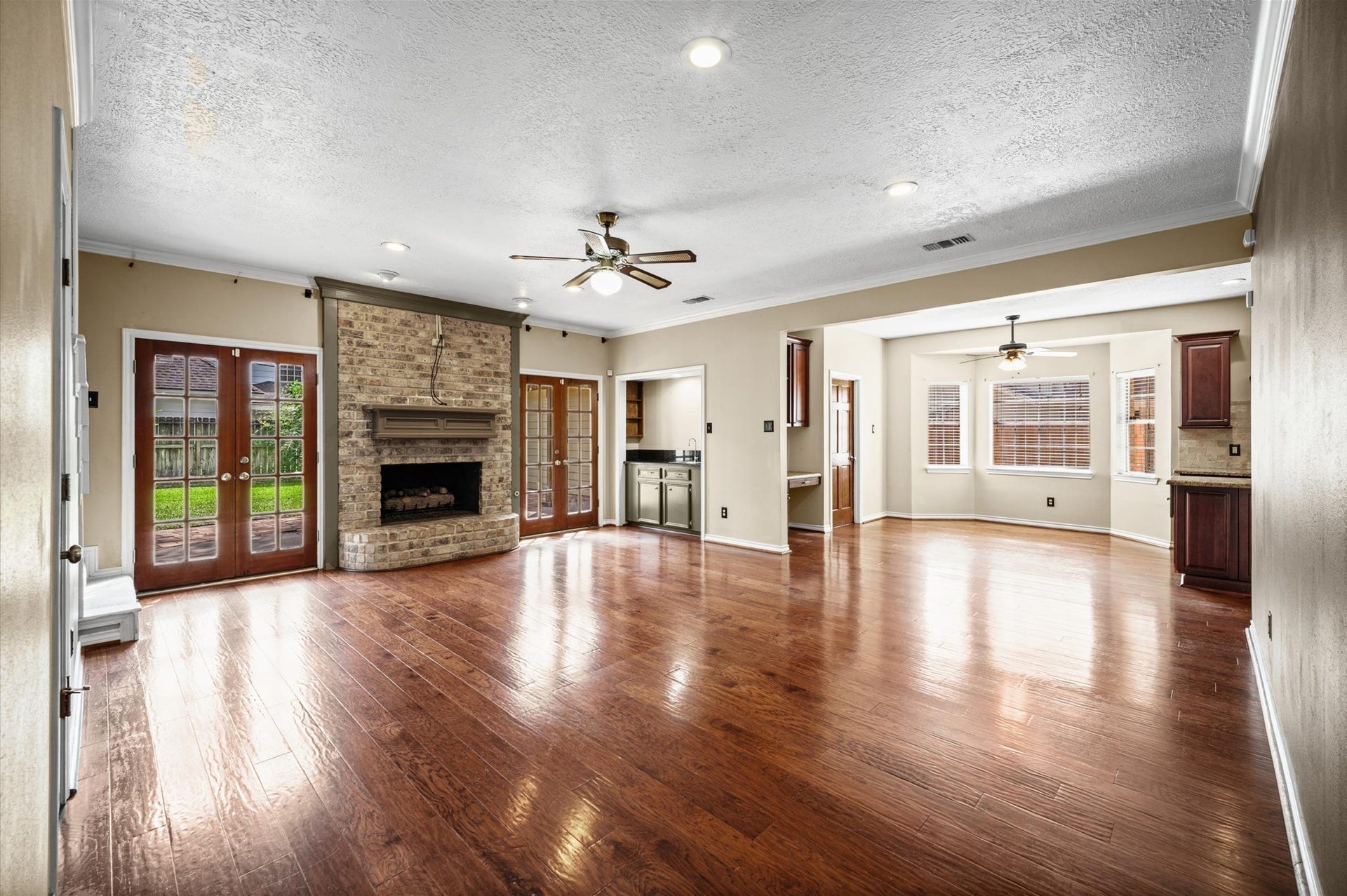 13126 Lemur Lane, Cypress, TX 77429 Spacious living room with beautiful brick fireplace, two sets of french doors, wood floors and a wet bar- perfect for gathering and entertaining.