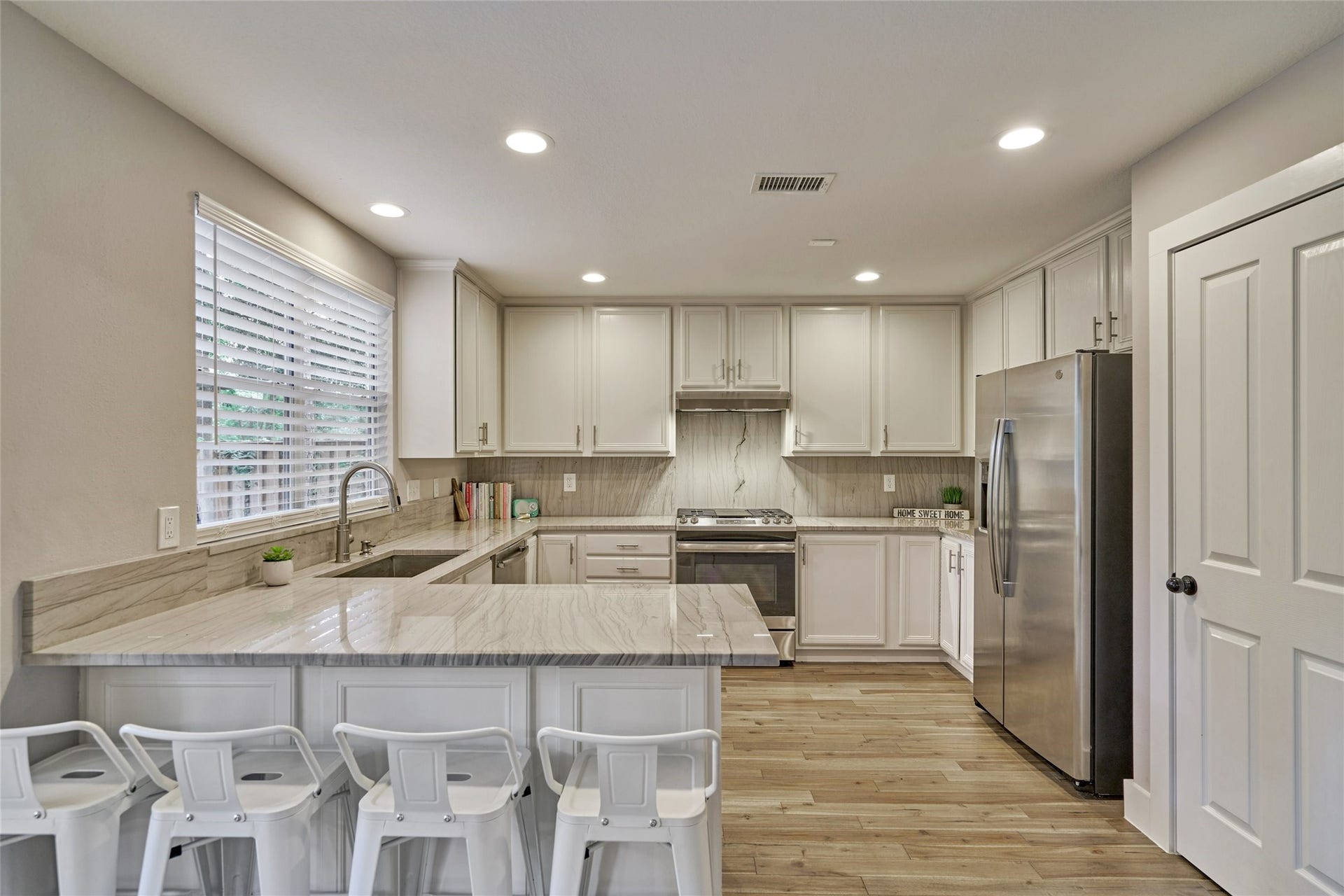 38 E Gaslight Place, The Woodlands, TX 77382 Another view of the kitchen. The gorgeous Quartz counters and backsplash add texture to the space. The stainless steel refrigerator also stays with the home.