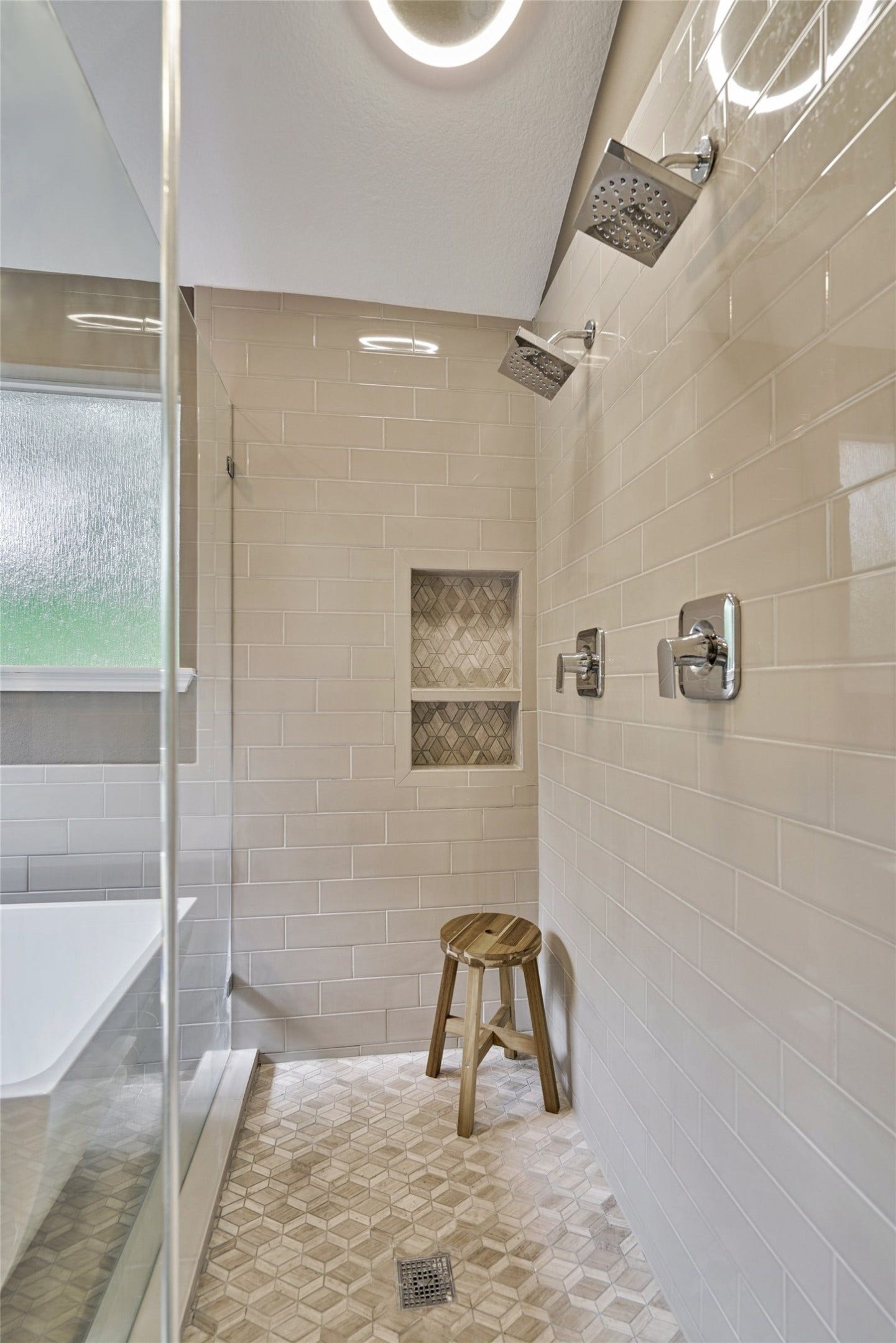 38 E Gaslight Place, The Woodlands, TX 77382 The large glass shower in the primary bathroom. Dual shower heads and custom tile flooring!