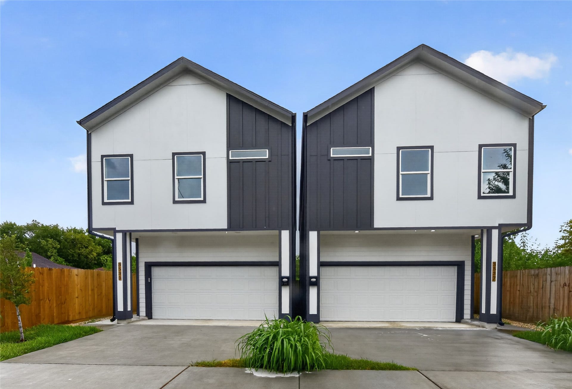 A striking new-construction exterior featuring a private driveway for guest parking and a two-car garage with a convenient side entrance. Clean curb appeal, thoughtful design, and everyday convenienceall from the moment you arrive.
