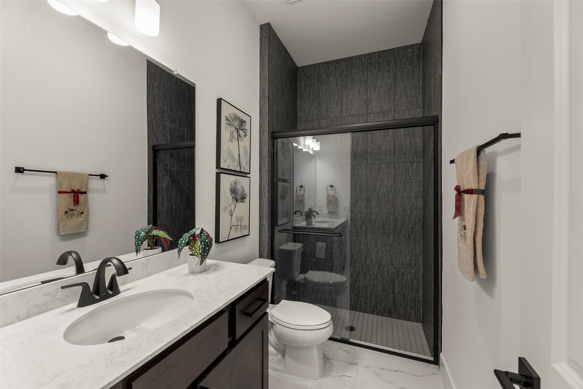 2015 Jade Manor Drive, Rosenberg, TX 77469 Elegant bathroom featuring a sleek glass-enclosed shower, modern fixtures, and a marble countertop, accented by stylish decor and artwork.