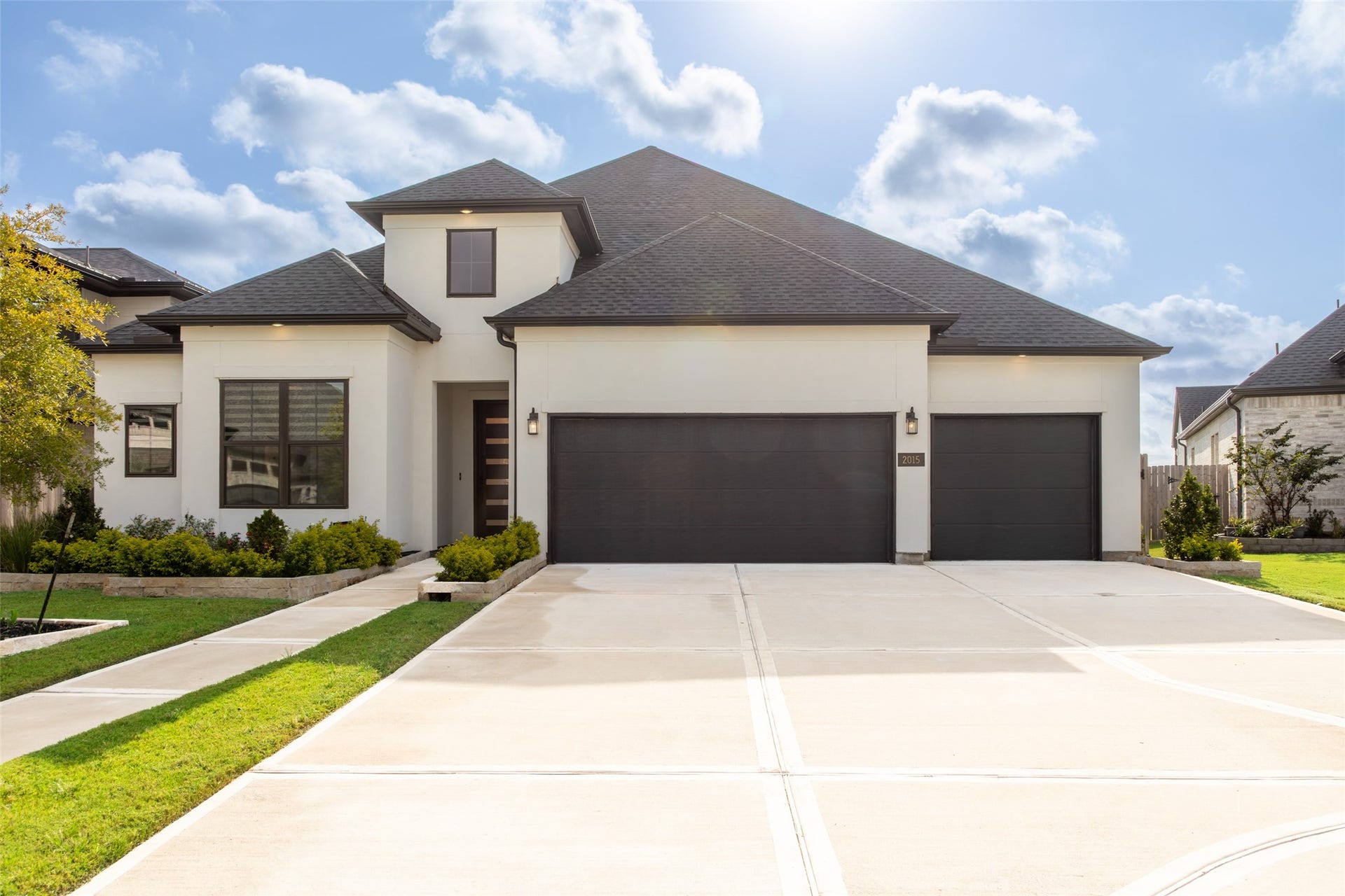 2015 Jade Manor Drive, Rosenberg, TX 77469 Modern home with black and white exterior, featuring a spacious three-car garage.
