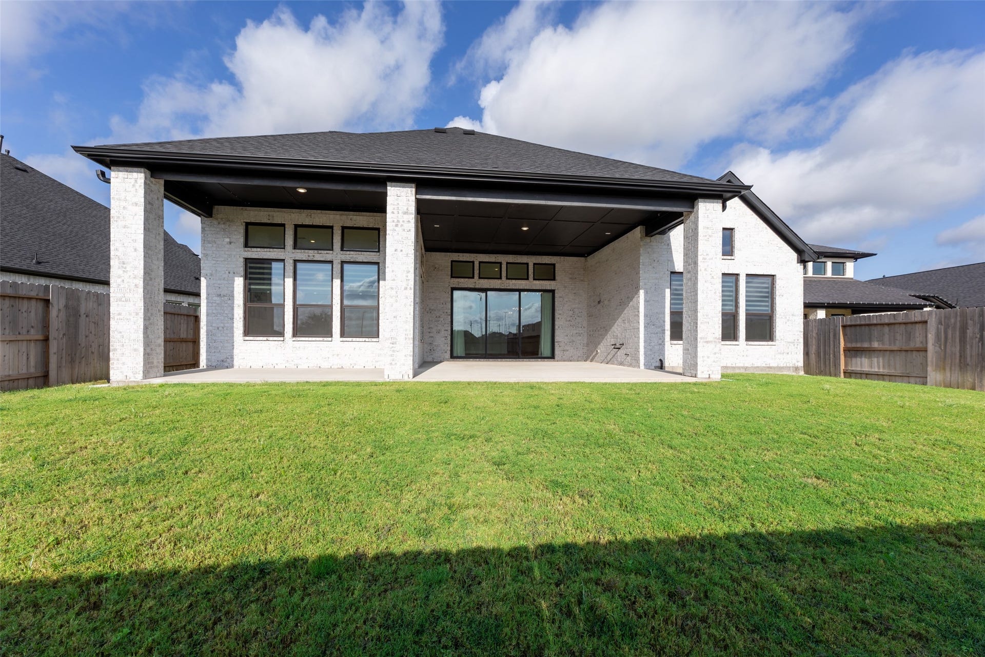 2015 Jade Manor Drive, Rosenberg, TX 77469 Maintained backyard with a covered patio, perfect for outdoor entertainment and relaxation, complemented by a modern exterior and large windows for natural light.
