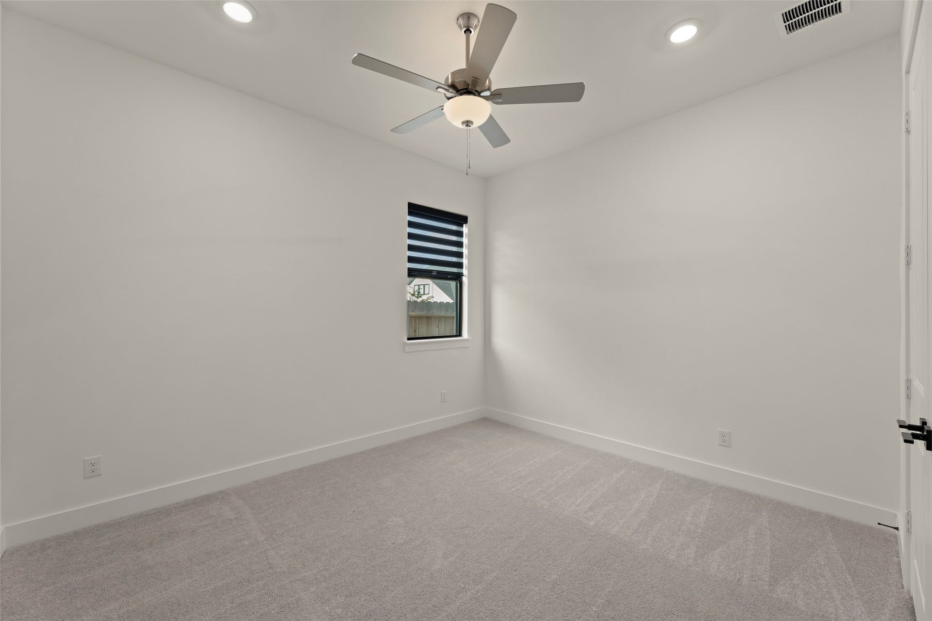2015 Jade Manor Drive, Rosenberg, TX 77469 Bedroom featuring fresh carpeting, a modern ceiling fan, and recessed lighting, complemented by a window with sleek blinds.