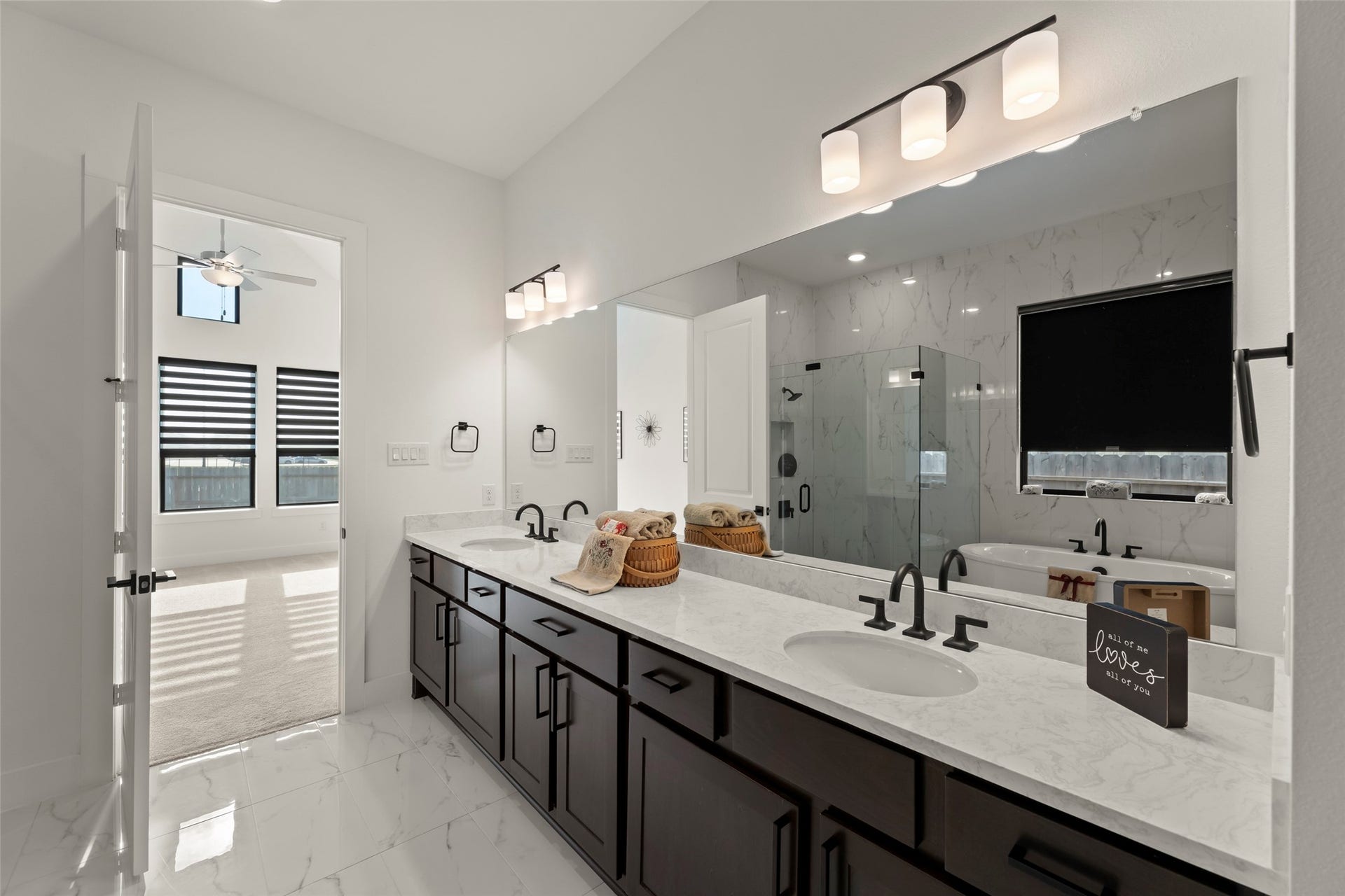 2015 Jade Manor Drive, Rosenberg, TX 77469 Luxurious bathroom featuring a double vanity with elegant fixtures, a spacious glass-enclosed shower, and a relaxing soaking tub, all complemented by modern lighting and sleek tile flooring.