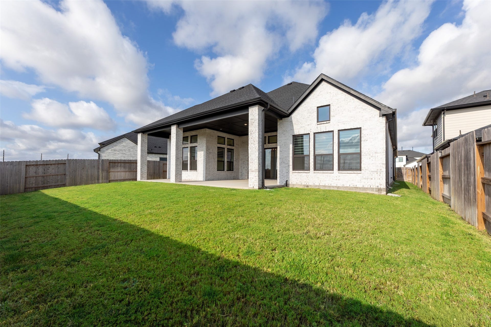 2015 Jade Manor Drive, Rosenberg, TX 77469 Expansive backyard with a covered patio, perfect for outdoor relaxation and entertainment, set against a backdrop of clear blue skies.