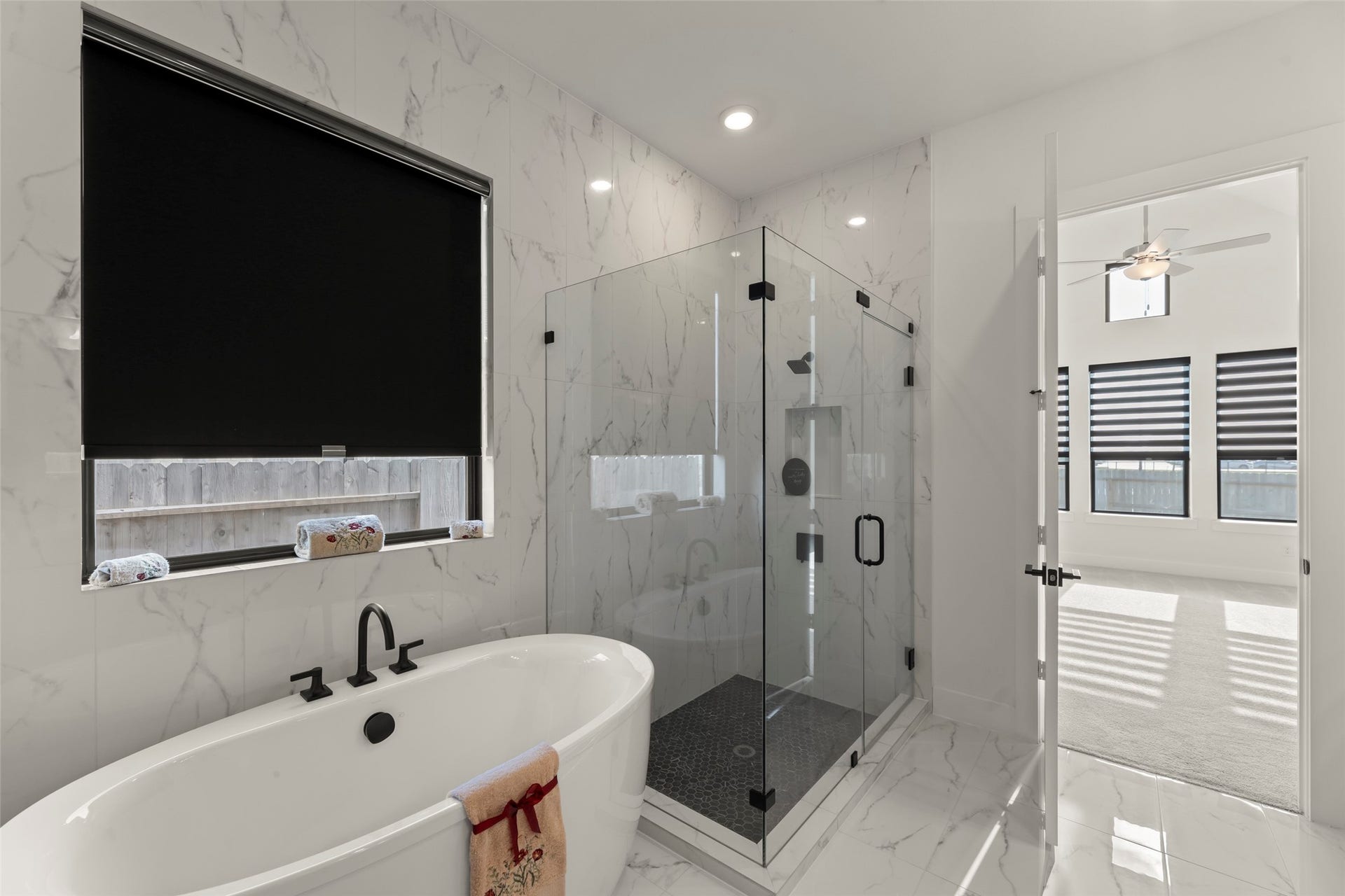 2015 Jade Manor Drive, Rosenberg, TX 77469 Freestanding tub and a spacious glass-enclosed shower, enhanced by elegant marble-patterned walls and floors.