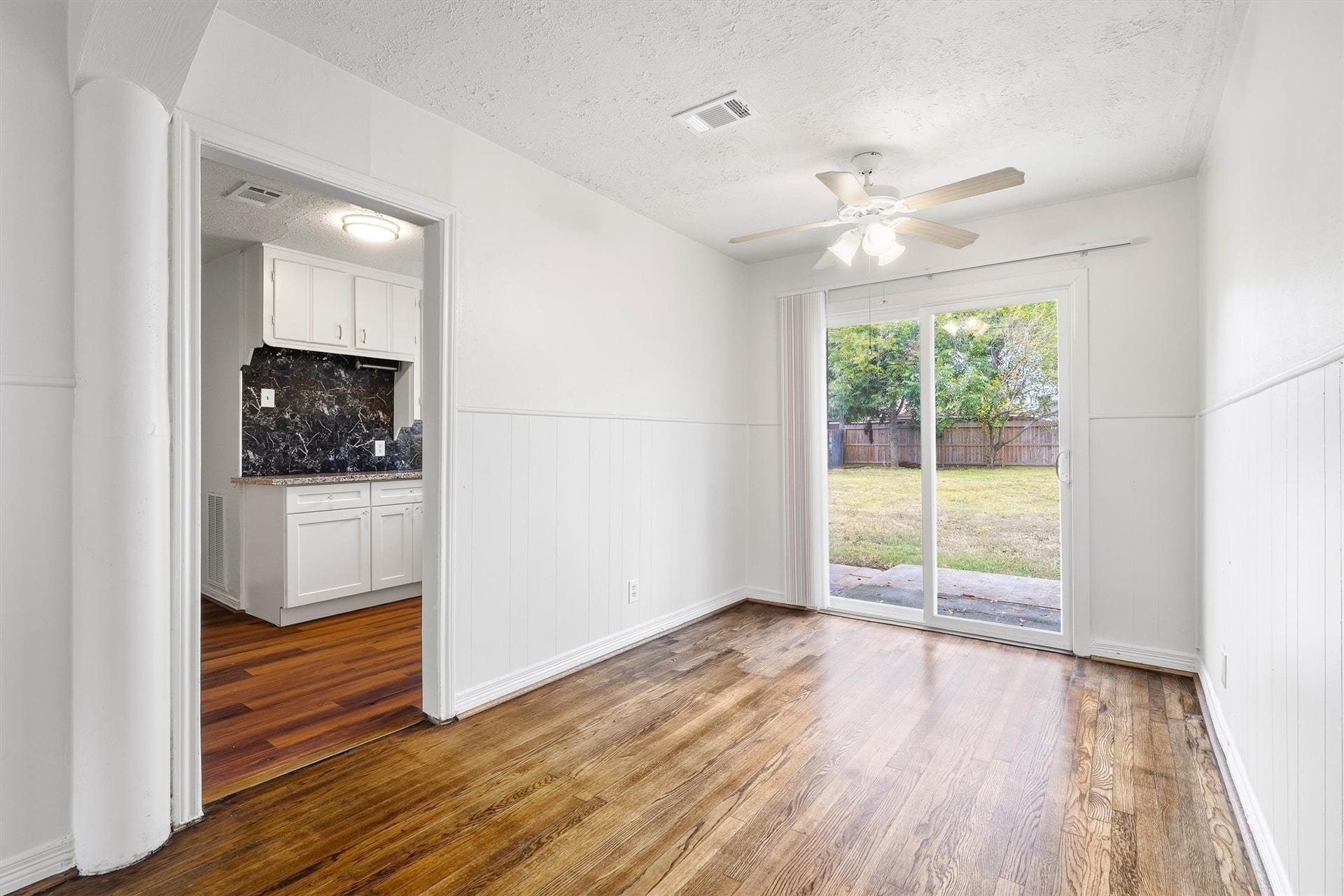 6630 Maybank Drive, Houston, TX 77055 Bright dining area with hardwood floors, sliding glass doors leading to a spacious backyard, and an adjacent kitchen featuring marble-patterned backsplash.